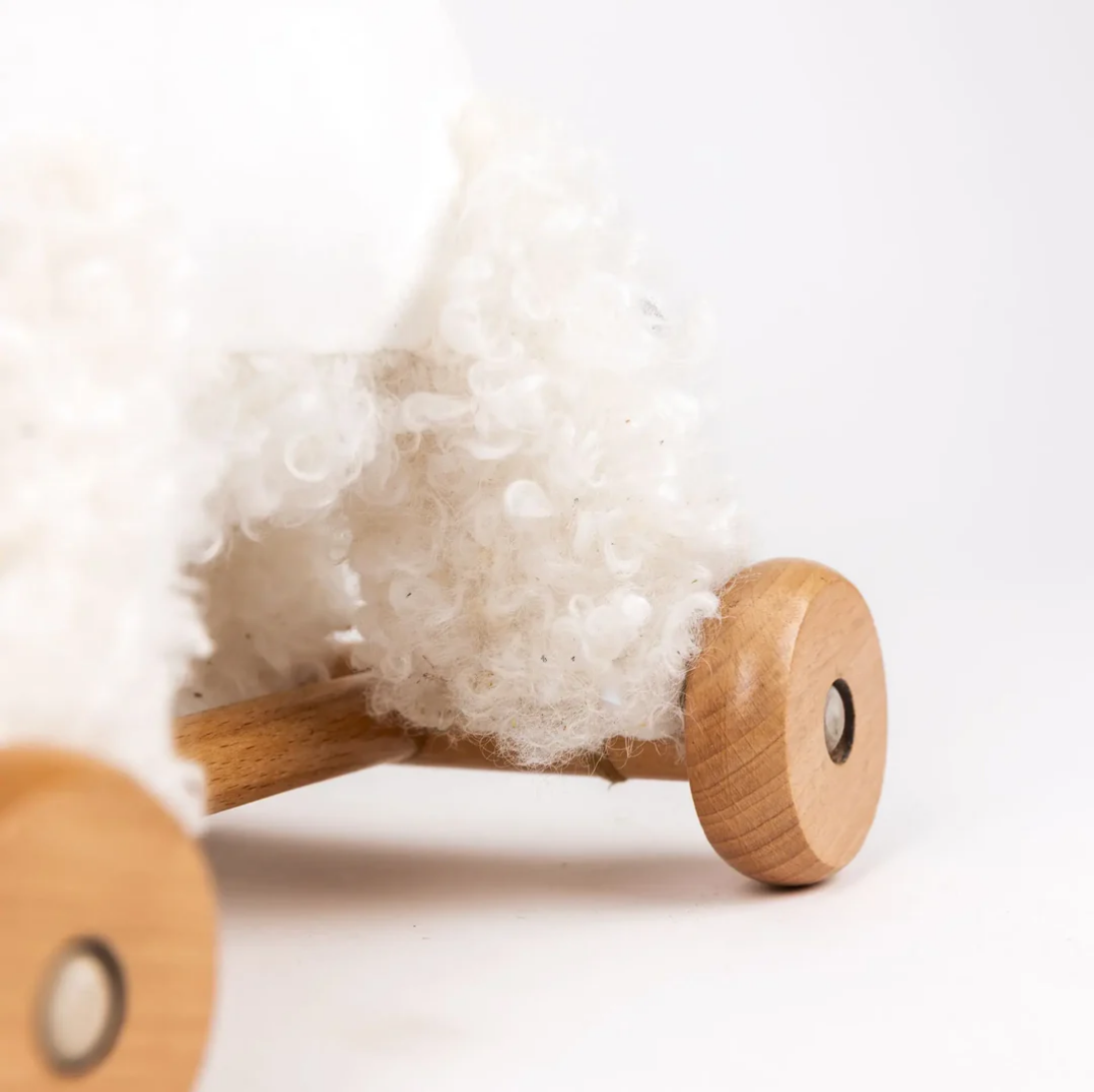 Close-up of a wooden toy with fluffy white material on a light background