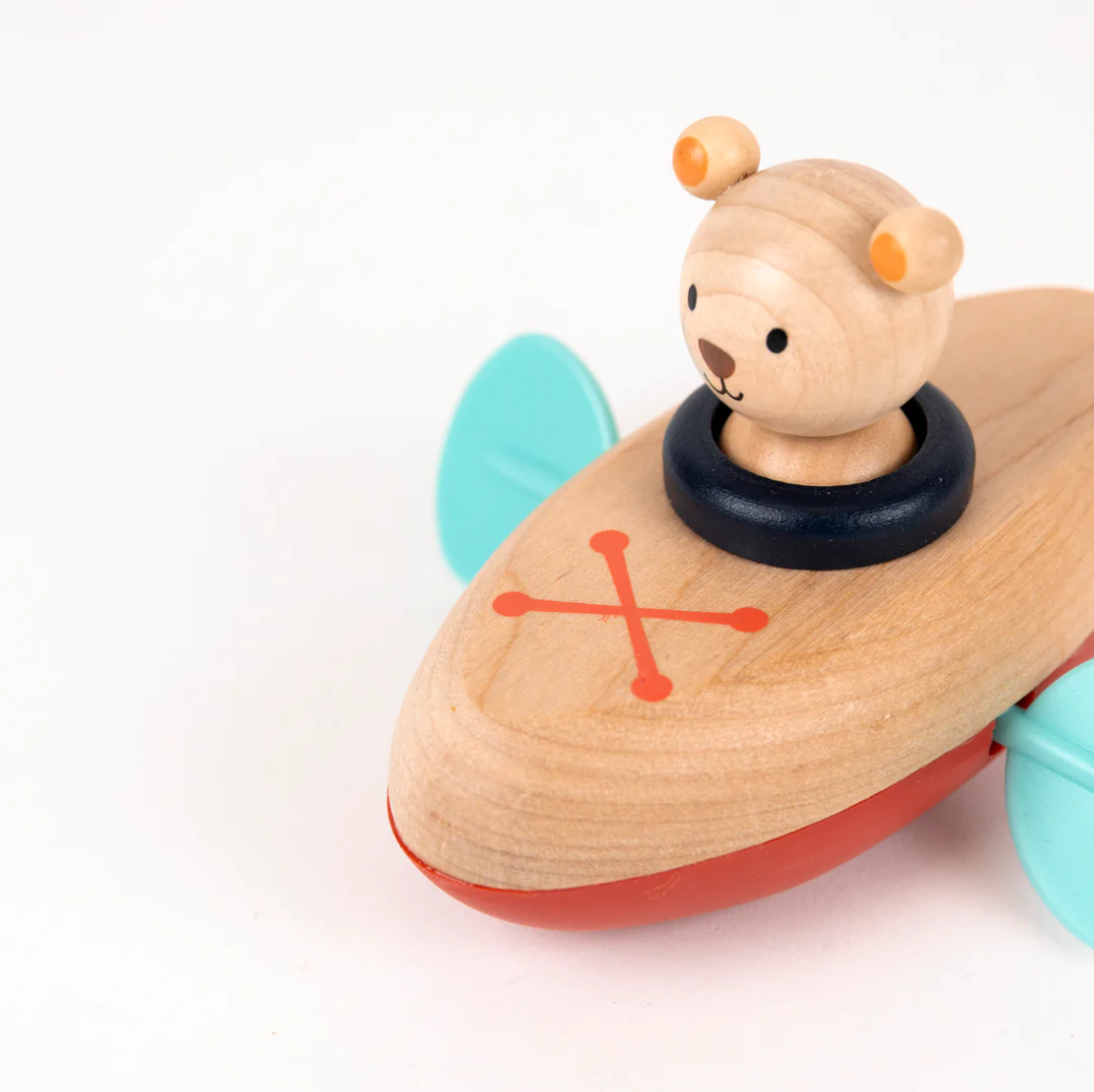 Wooden toy boat with a teddy bear figure on a white background