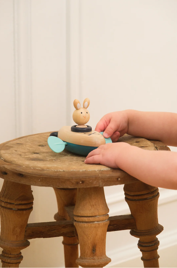 Child's hand interacting with a wooden toy on a small wooden table.
