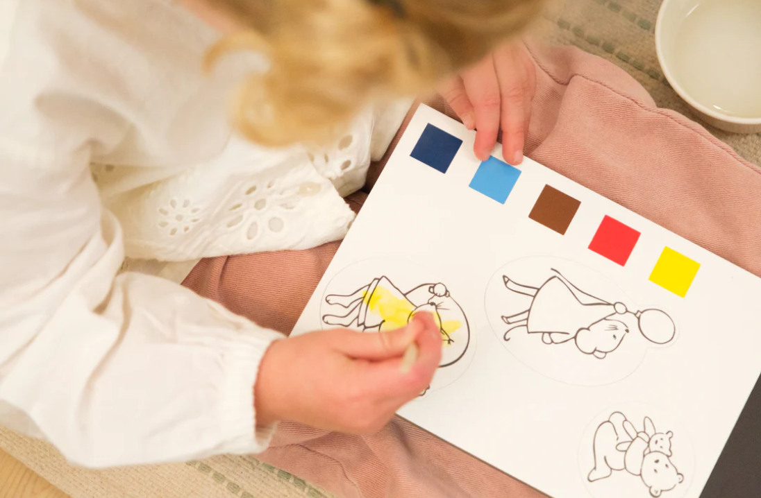 Child coloring a picture with color swatches