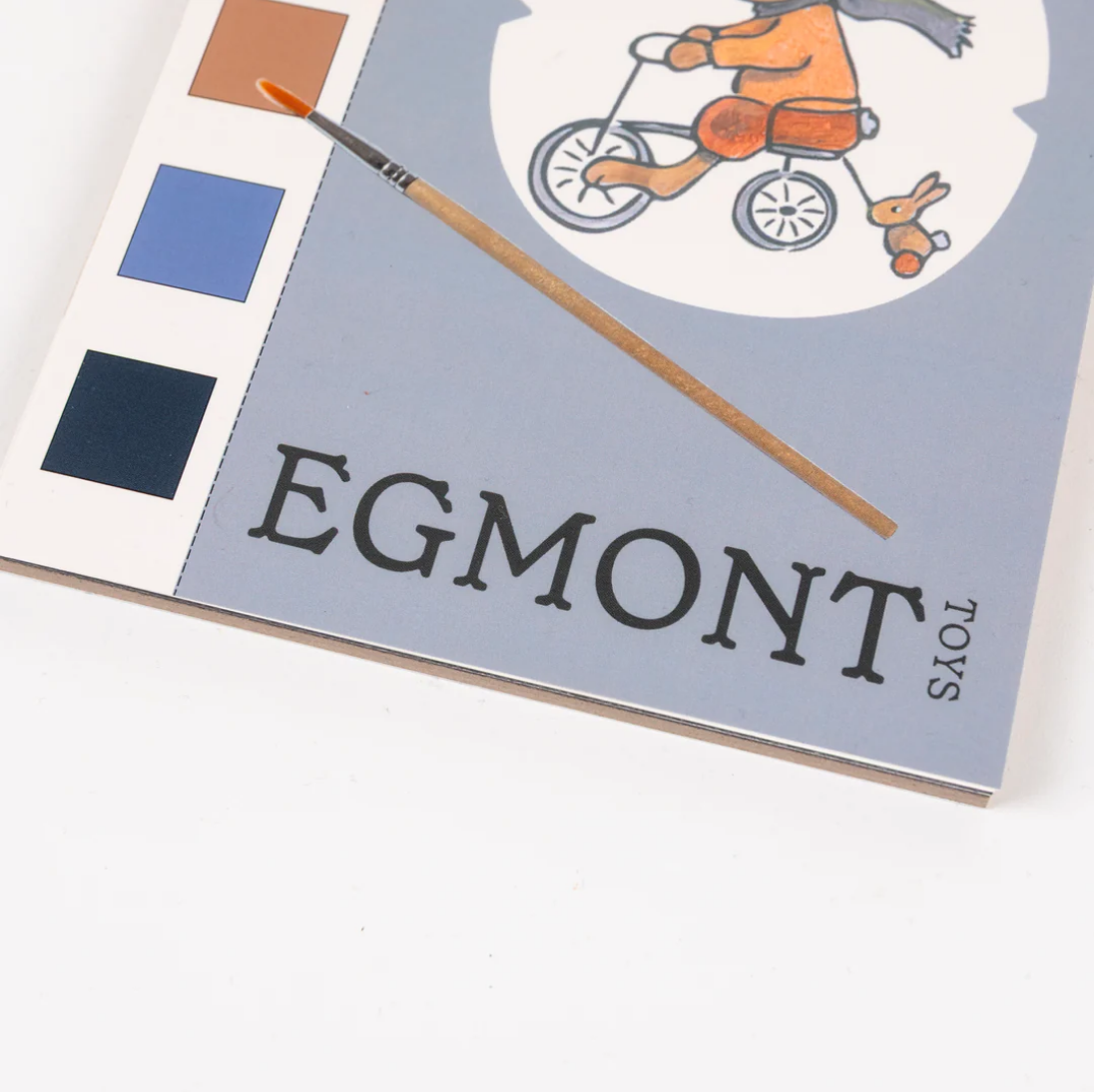 Egmont Toys book with a child on a bike illustration and a paintbrush on a white background
