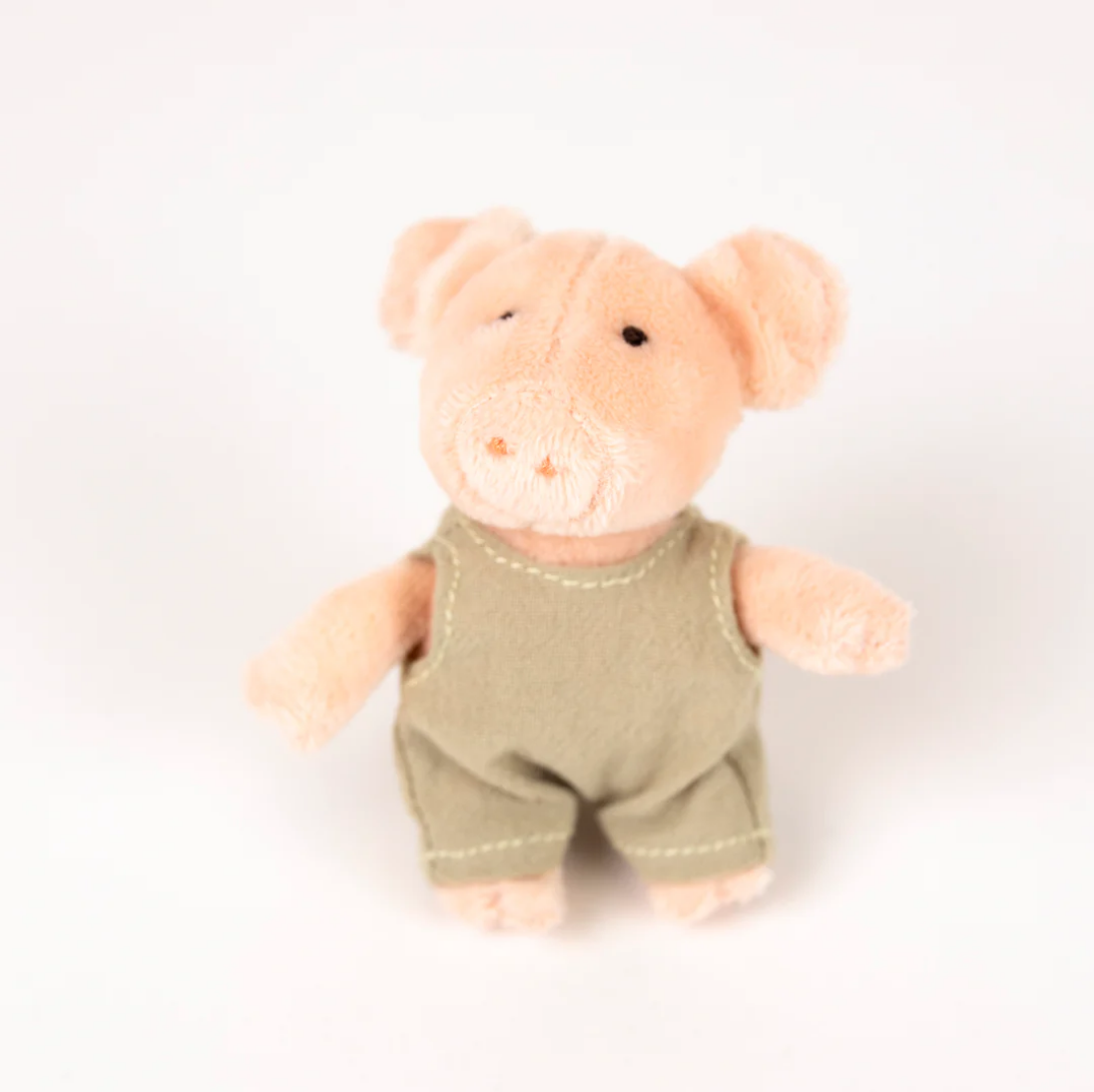 Plush toy pig wearing a green outfit on a white background
