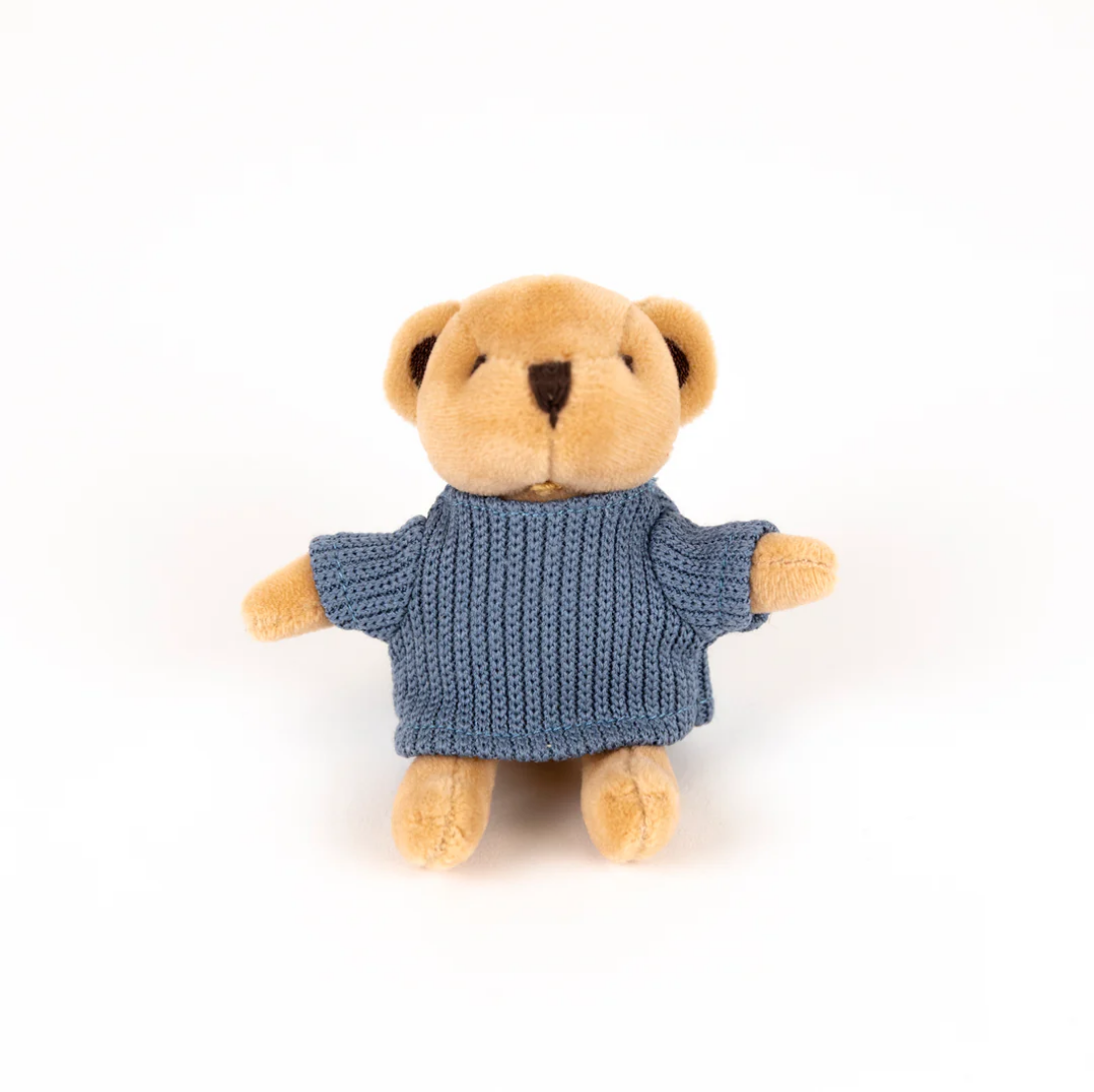 Stuffed teddy bear wearing a blue knitted sweater on a white background