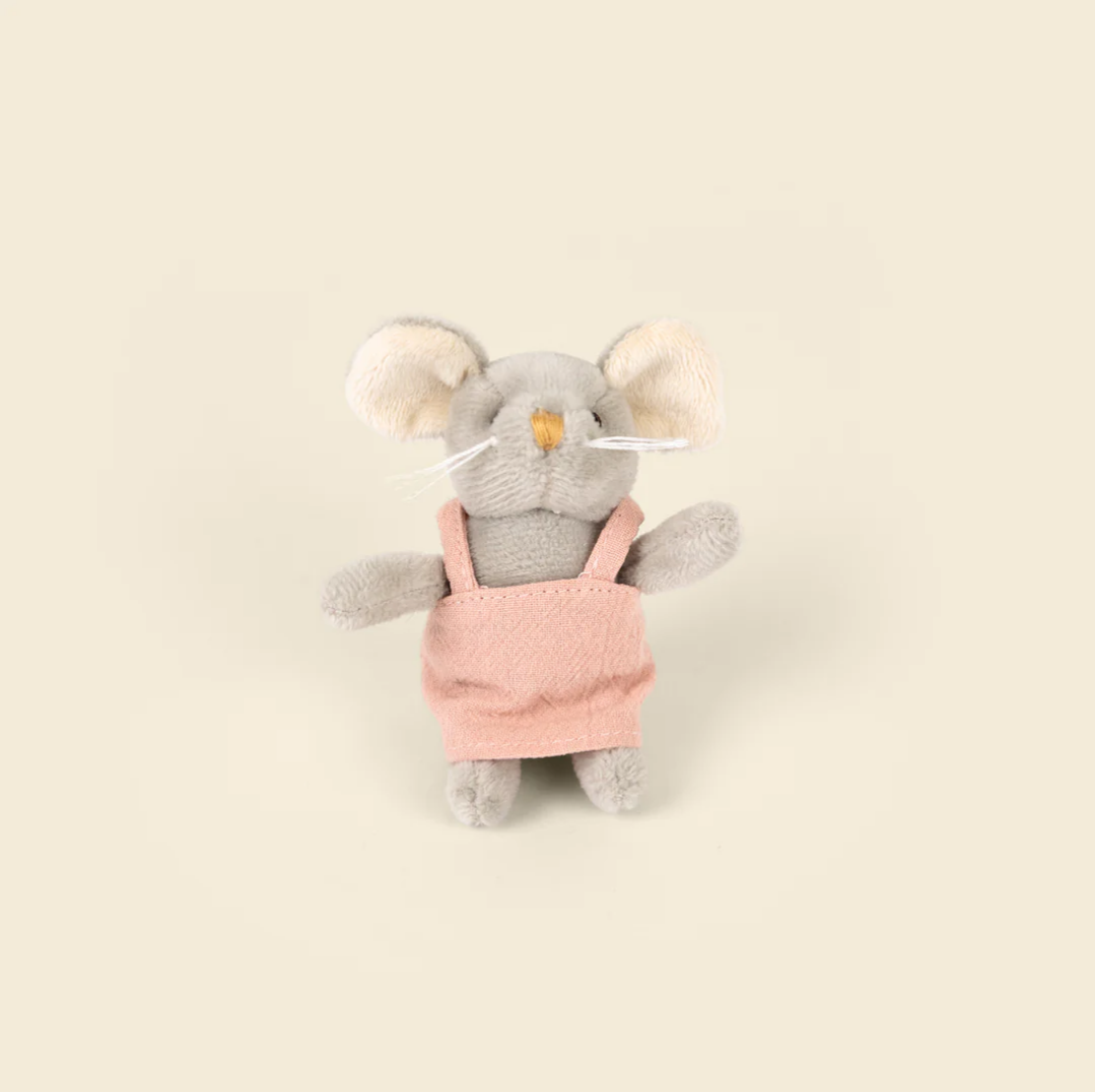 Plush toy mouse in a pink outfit on a beige background