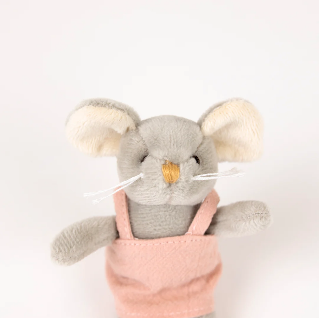 Plush toy mouse in pink overalls on a white background