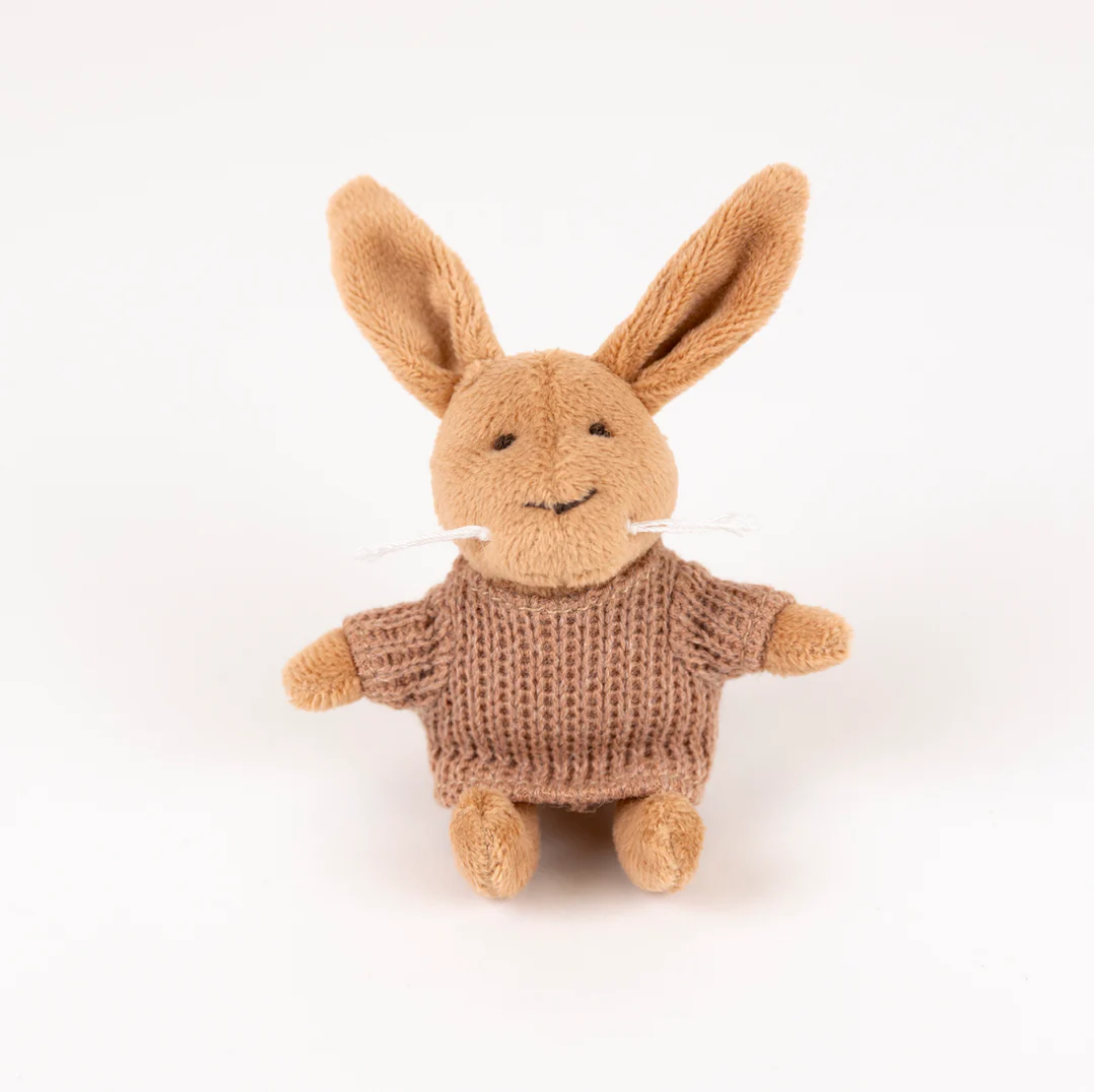 Knitted brown bunny toy with a sweater on a white background