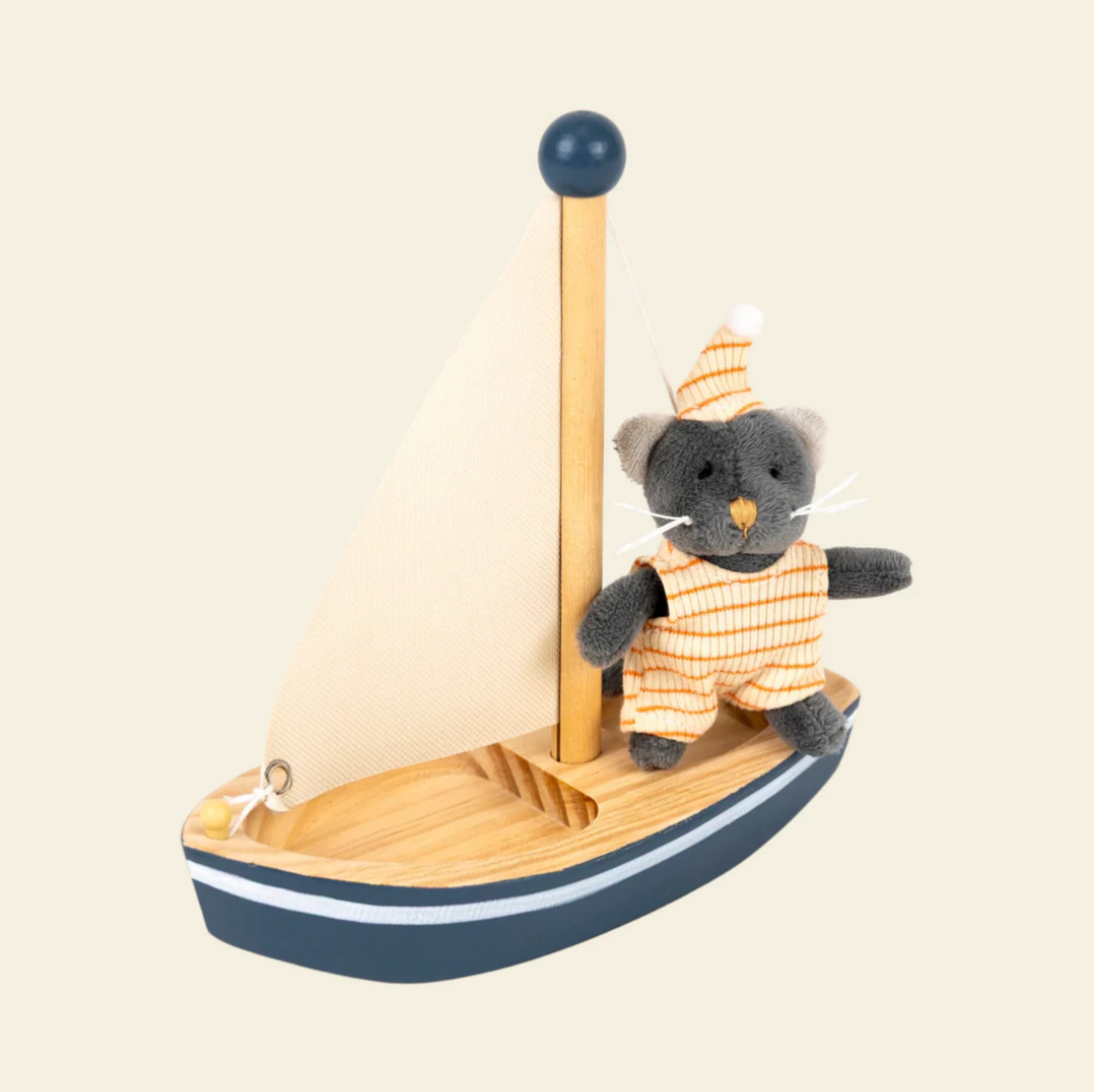 Stuffed toy mouse in a striped outfit on a small wooden boat with a sail against a beige background