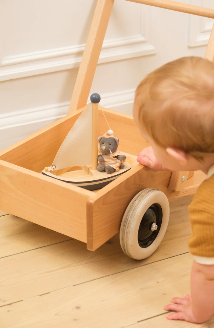 Child playing with a wooden toy boat on a wooden floor
