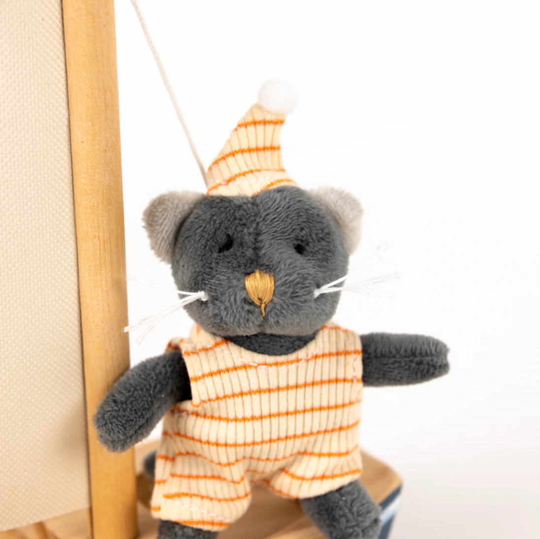 Plush toy cat in an orange outfit with a striped hat on a white background