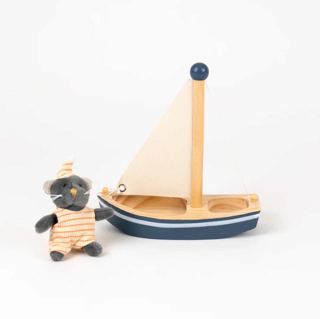Small toy boat with a sail and a toy mouse in a striped outfit on a white background