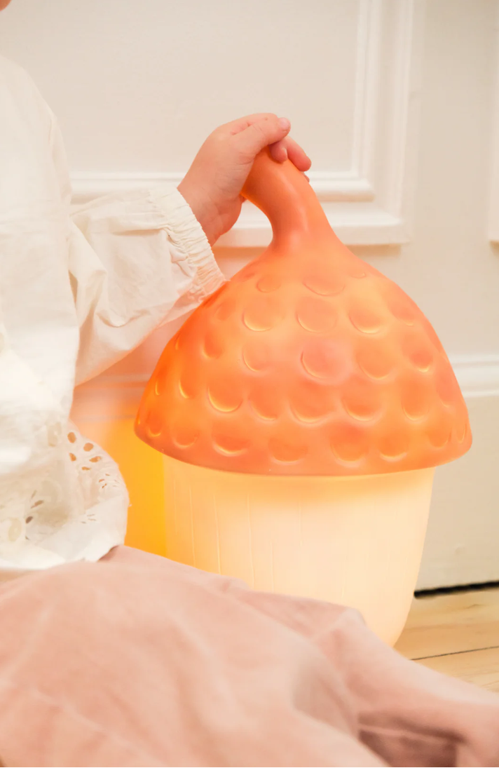 Person holding a gradient orange to white lamp with a textured surface.