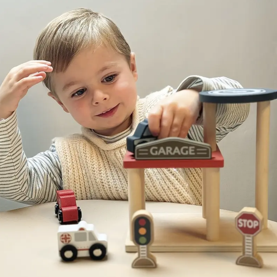 Child playing with a toy garage set on a table