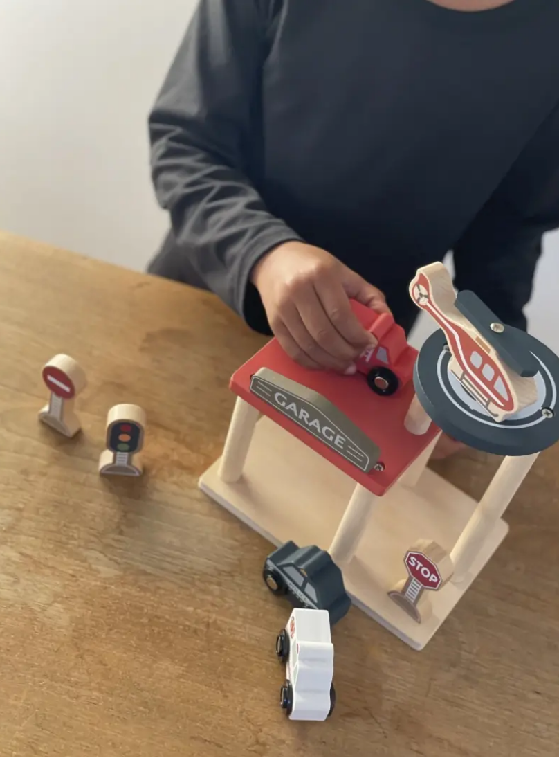 Child playing with a toy garage set on a wooden table