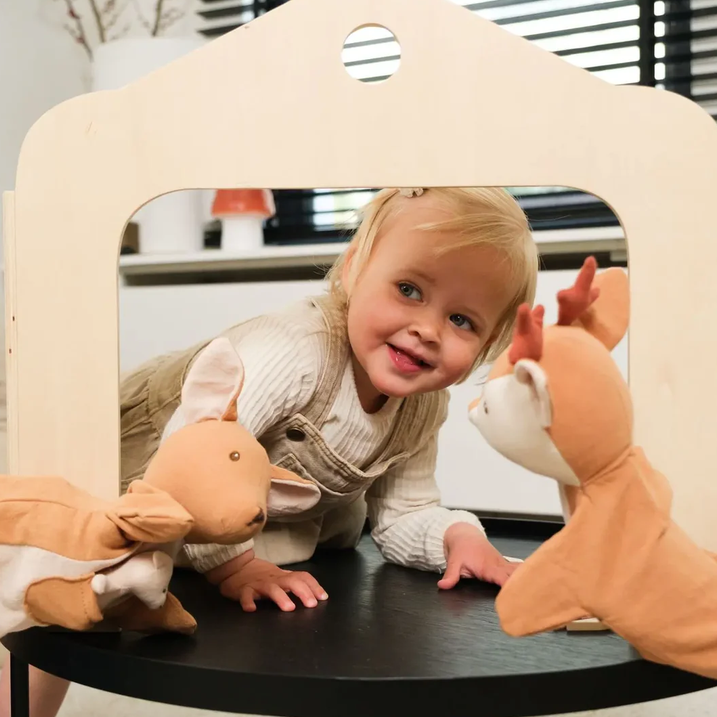 Child playing with toys on a round table in a room with a mirror reflecting the child.