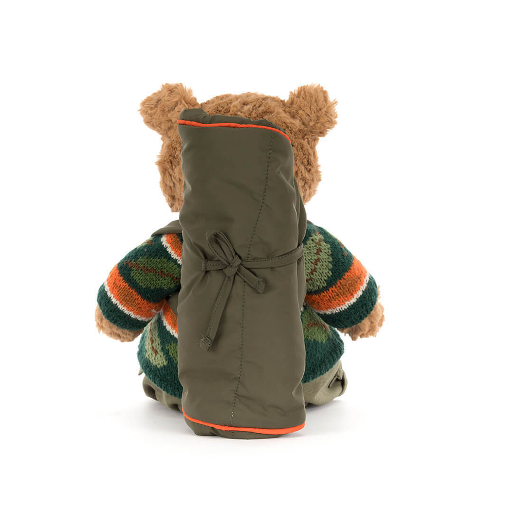 Teddy bear wearing a striped sweater and green coat on a white background