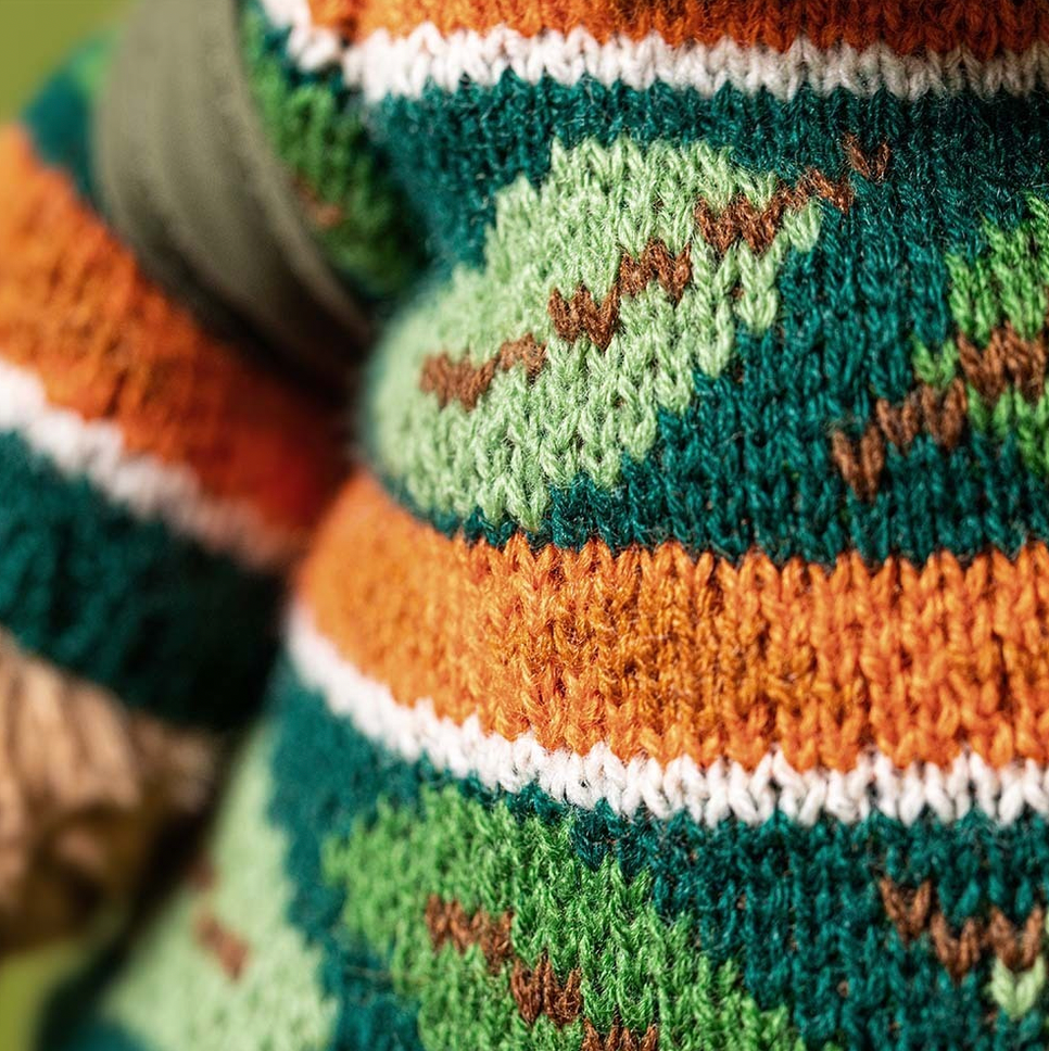 Close-up of a knitted item with a pattern of leaves and stems.