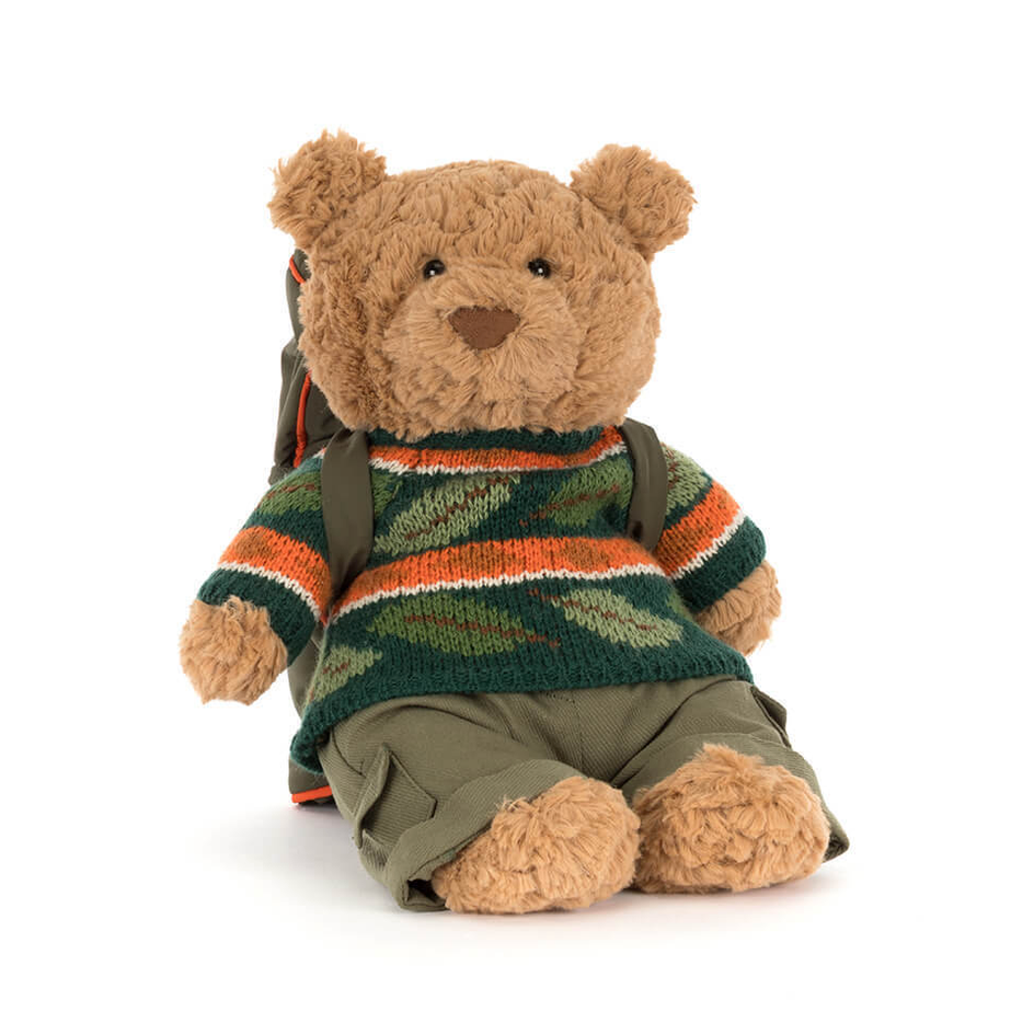 Stuffed teddy bear wearing a patterned sweater on a white background