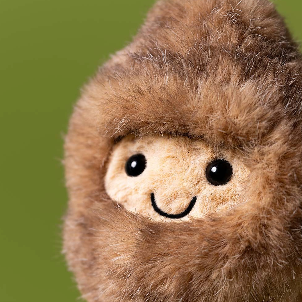 Close-up of a plush toy resembling a creature with a smiling face on a green background