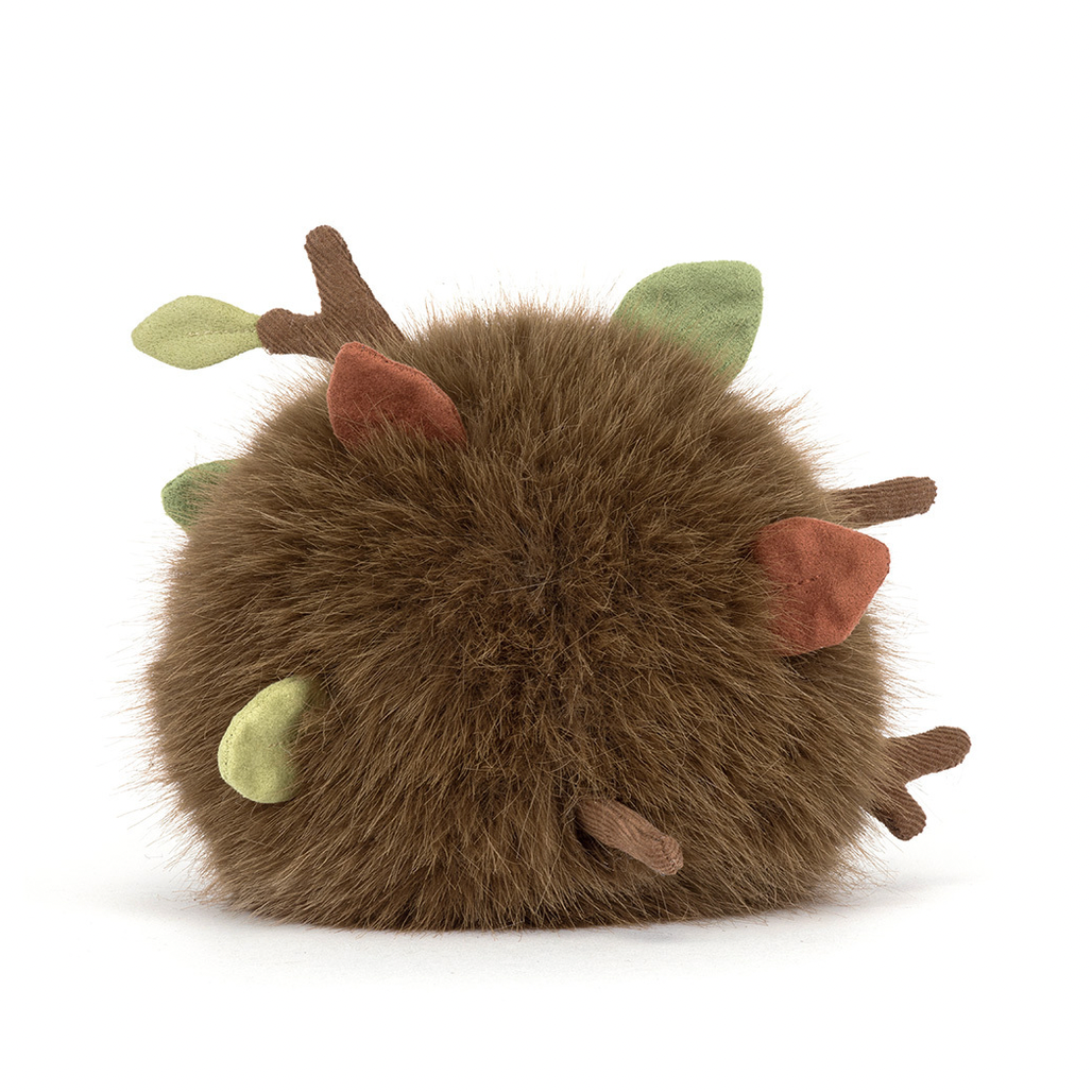 Plush toy resembling a creature with sticks and leaves on a white background