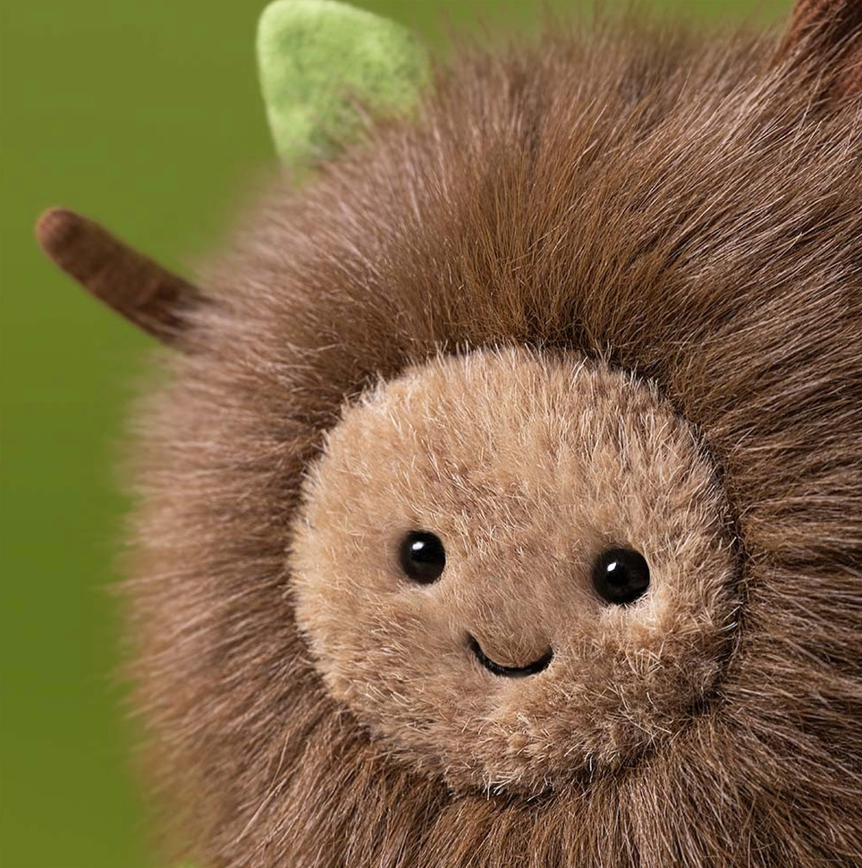 Plush toy hedgehog with a green leaf on a green background