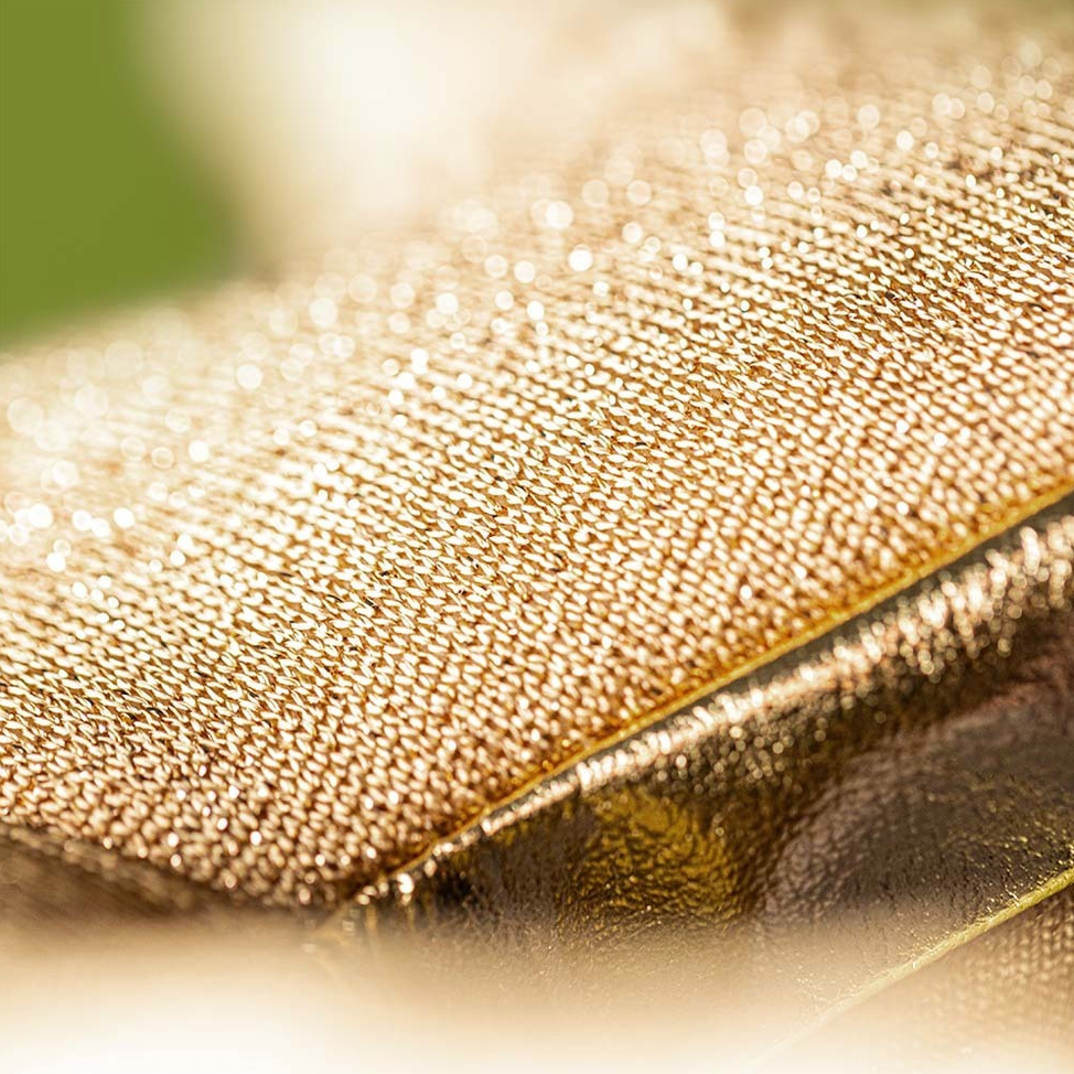 Close-up of a textured gold surface with a blurred green background