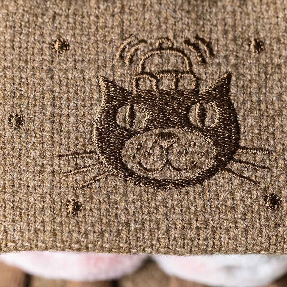 Embroidered cat design on a textured fabric background