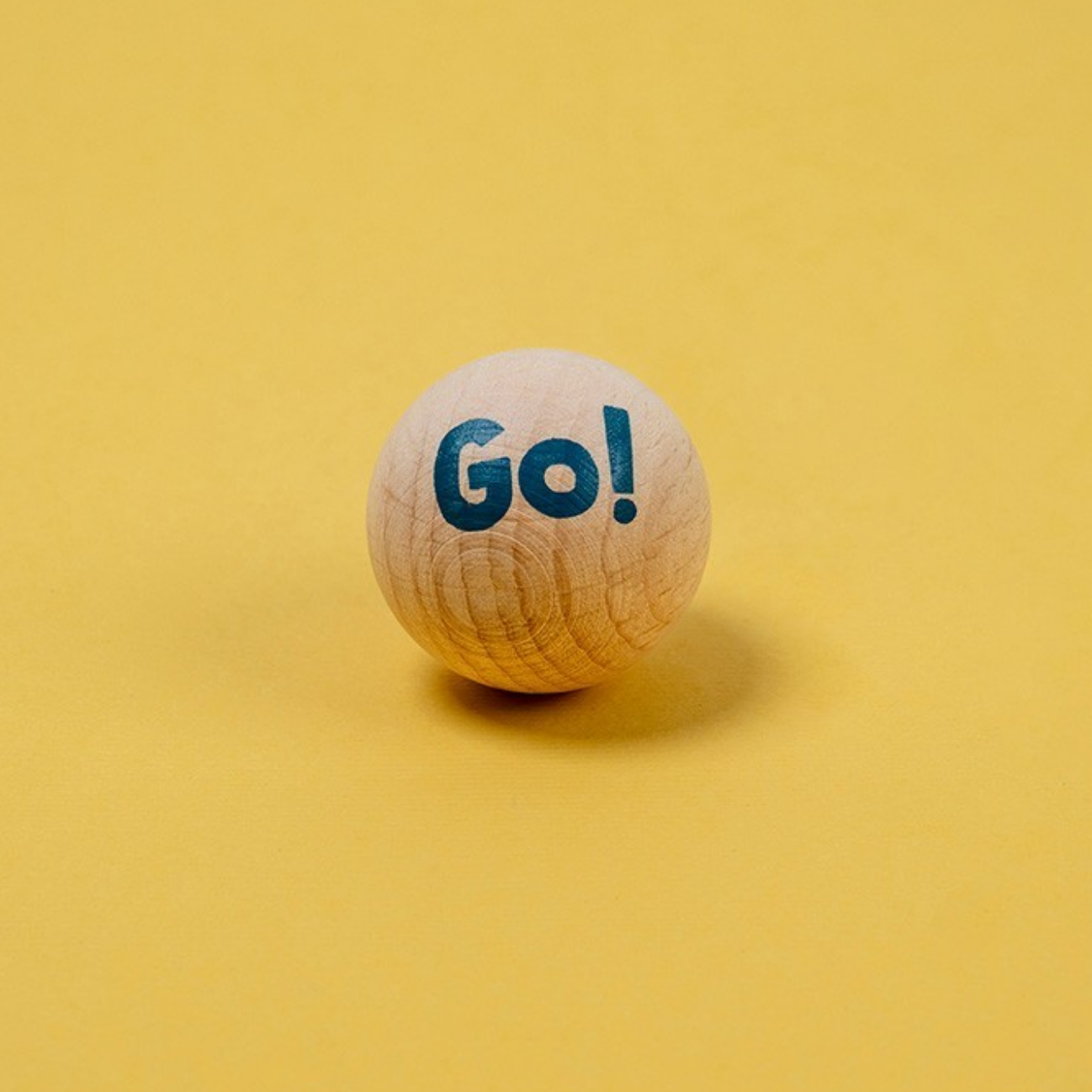 Wooden ball with 'Go!' text on a yellow background