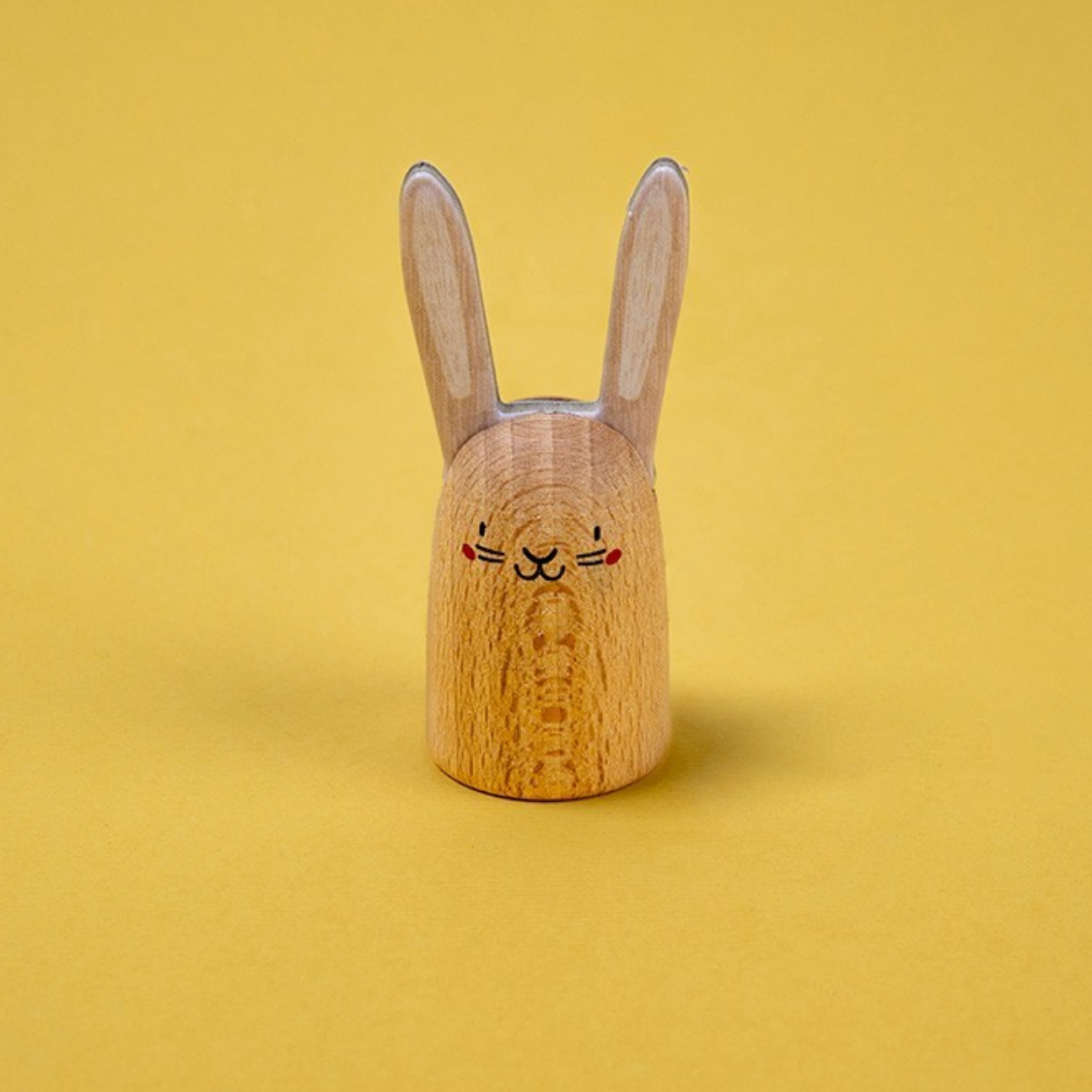 Wooden rabbit-shaped object on a yellow background