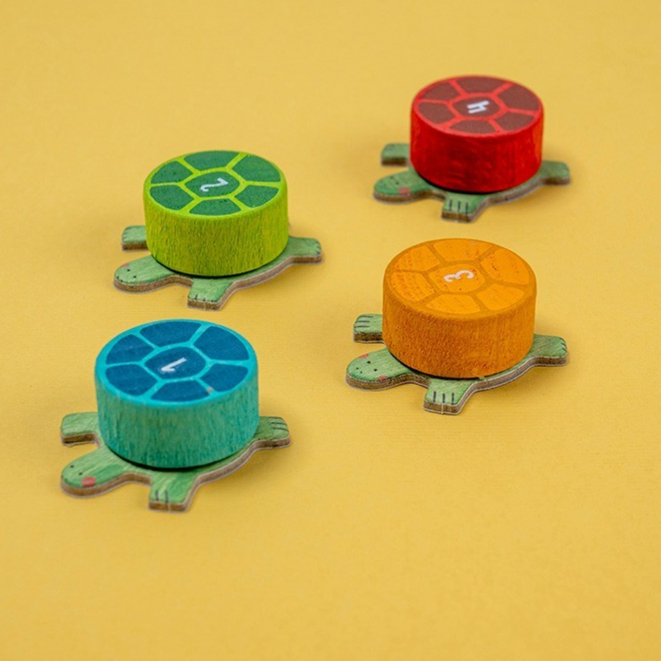 Four colorful turtle-shaped dice on a yellow background