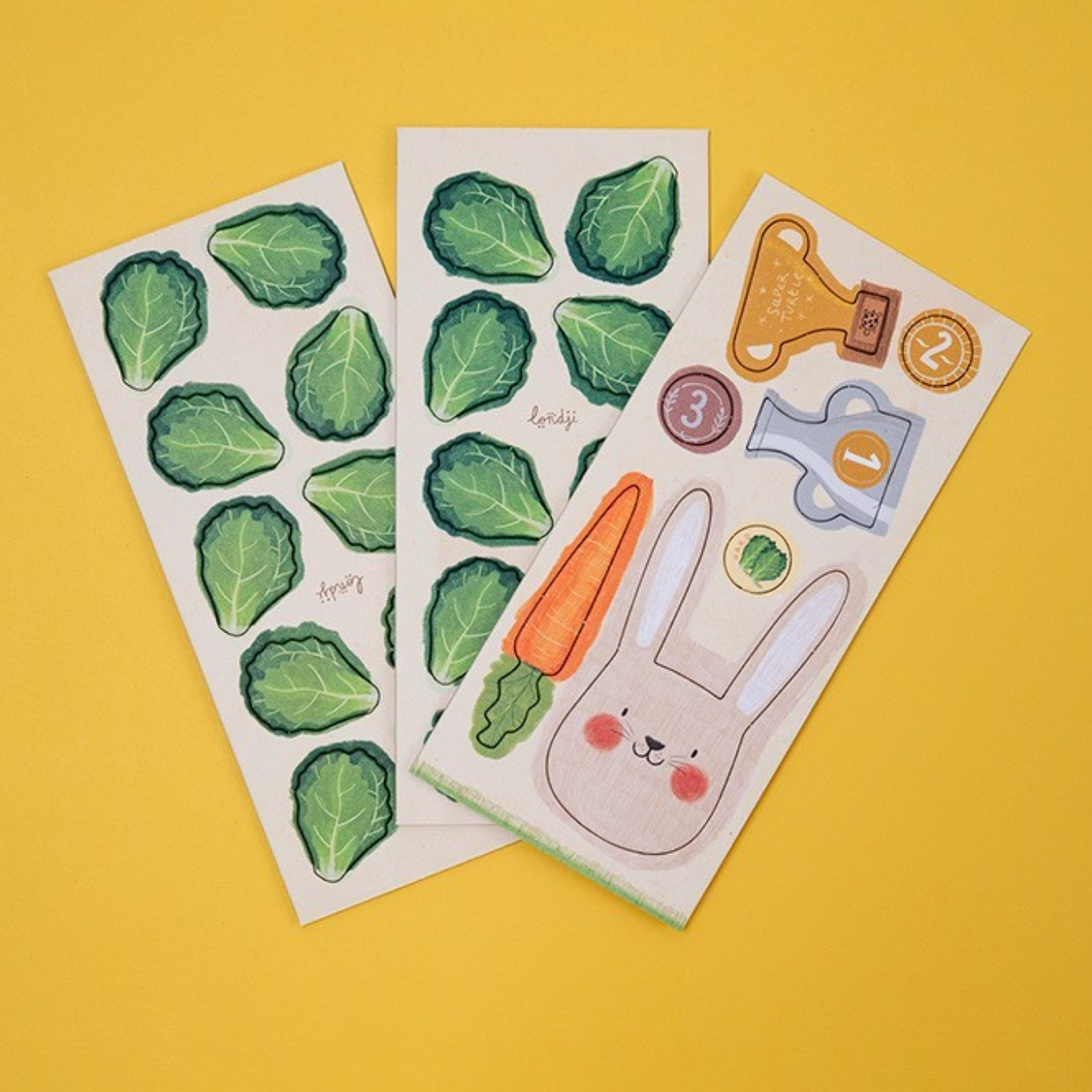 Three sheets of stickers with green leaves, a carrot, and a rabbit on a yellow background