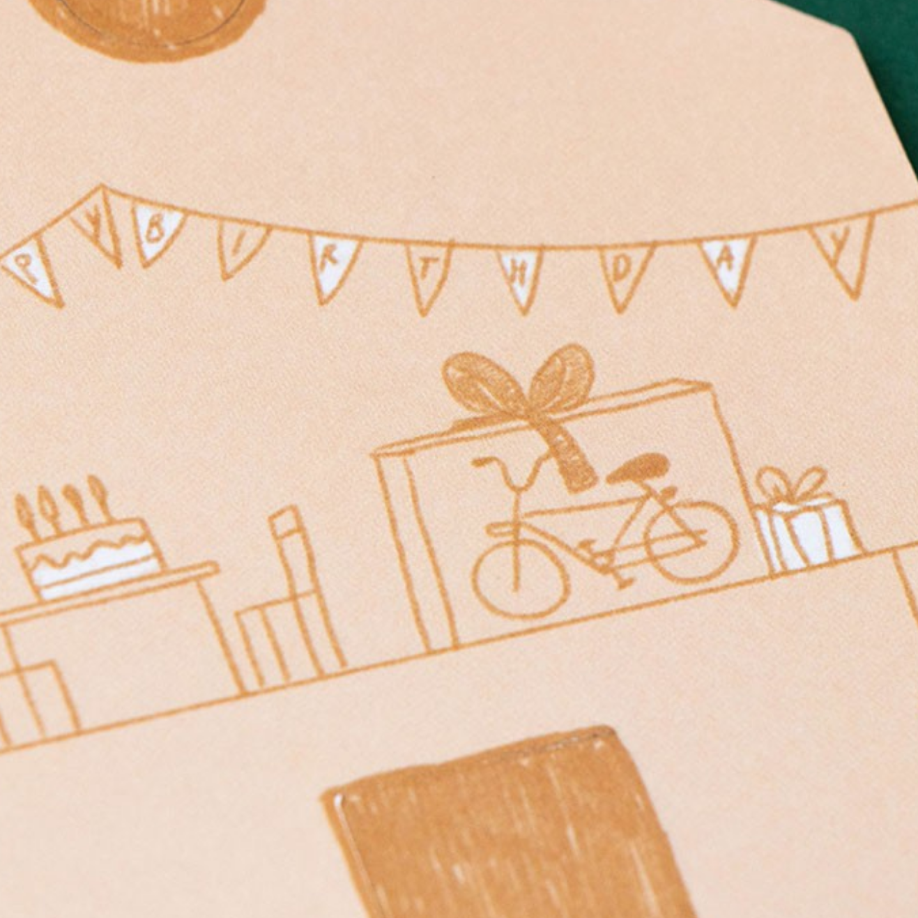 Beige paper with brown line art illustrations of a bicycle, gift box, cake, and other items on a green surface.