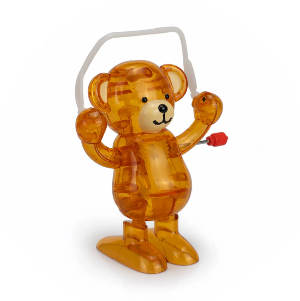 Transparent orange bear toy with a red wind-up knob on a white background