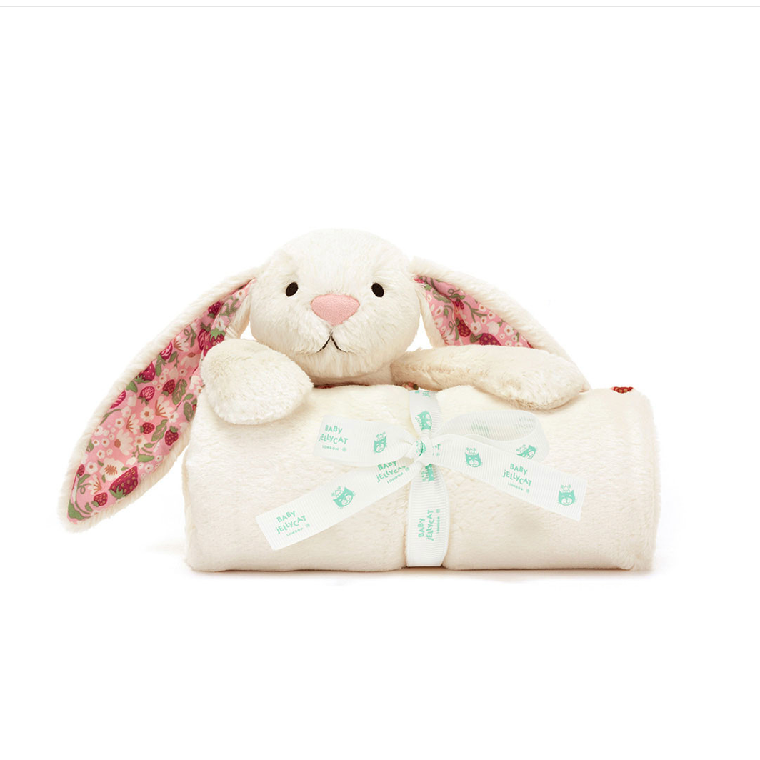 A plush bunny blankie with long cream ears and a pink floral pattern, shown wrapped in a cream blanket with a mint ribbon. Product text below reads 'Blossom Cream Bunny "Berry" Blankie' on a white background.