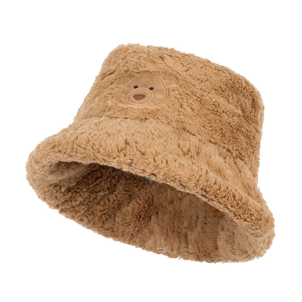 A plush tan bucket hat with a small embroidered bear face on the front