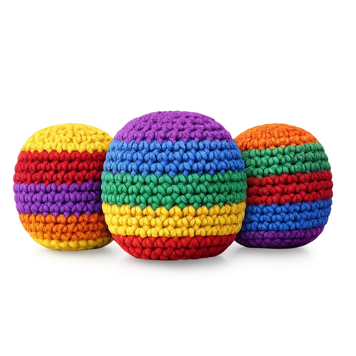 Three crocheted rainbow-colored footbags arranged together on a white background