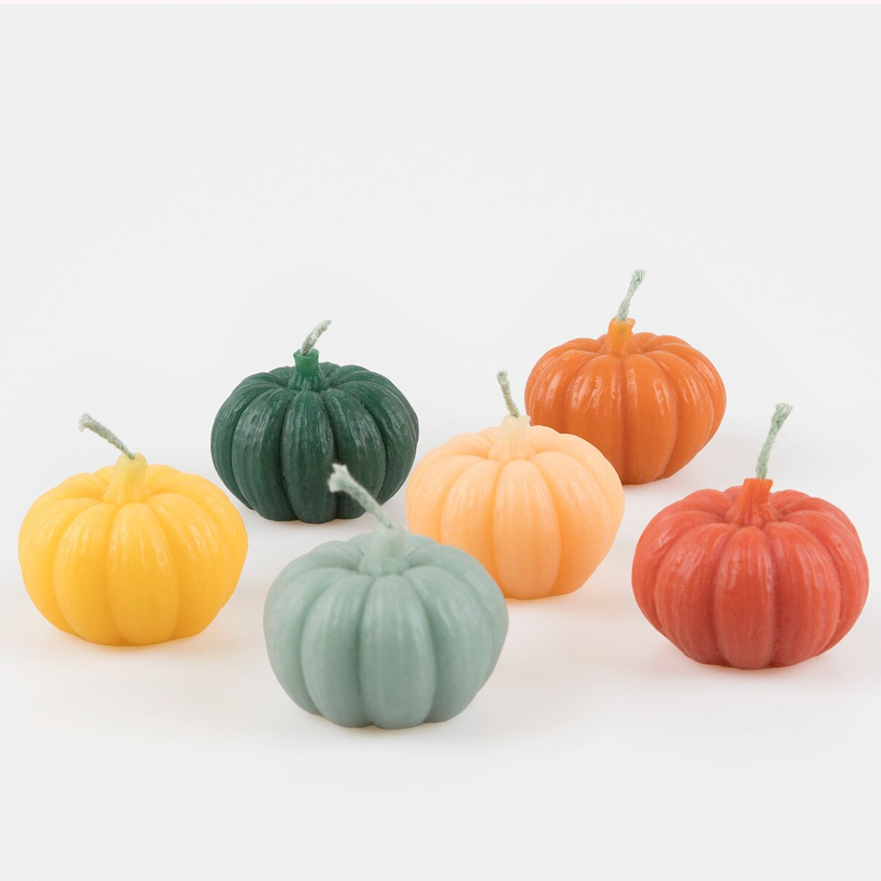Six small decorative pumpkins in assorted muted colors, including yellow, dark green, peach, orange, coral, and pale sage, arranged on a light gray background.