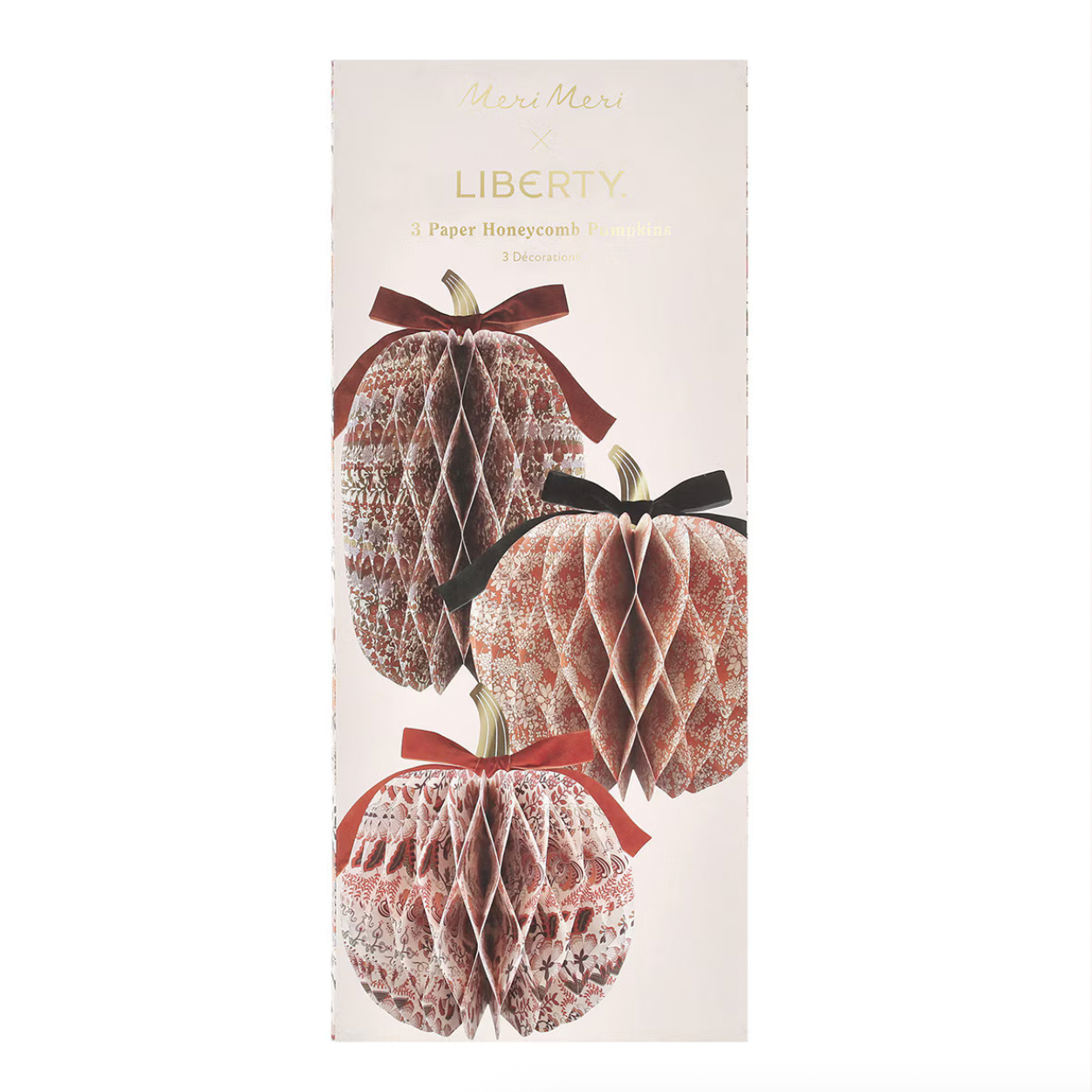 A tall rectangular package for 'Here Mera's Liberty' paper honeycomb ornaments, featuring illustrations of three textured honeycomb ornaments dusted in white and decorated with red and black ribbons, set against a white background.