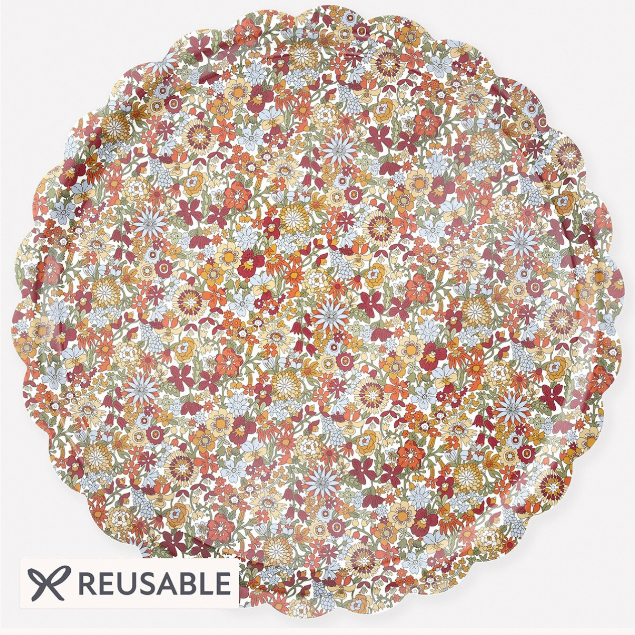 A reusable scalloped plate with a dense, multicolor floral pattern in shades of orange, red, yellow, green, and blue on a white base, shown on a light gray background with a 'REUSABLE' label at the bottom left.