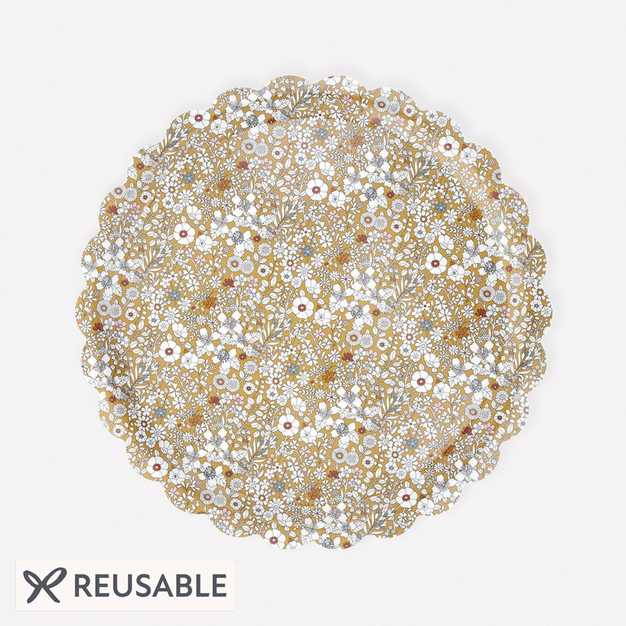 A round reusable plate with a scalloped edge, decorated with an intricate pattern of small white, yellow, and brown flowers and leaves. The word 'REUSABLE' is printed in black text at the bottom left with a small flower icon.