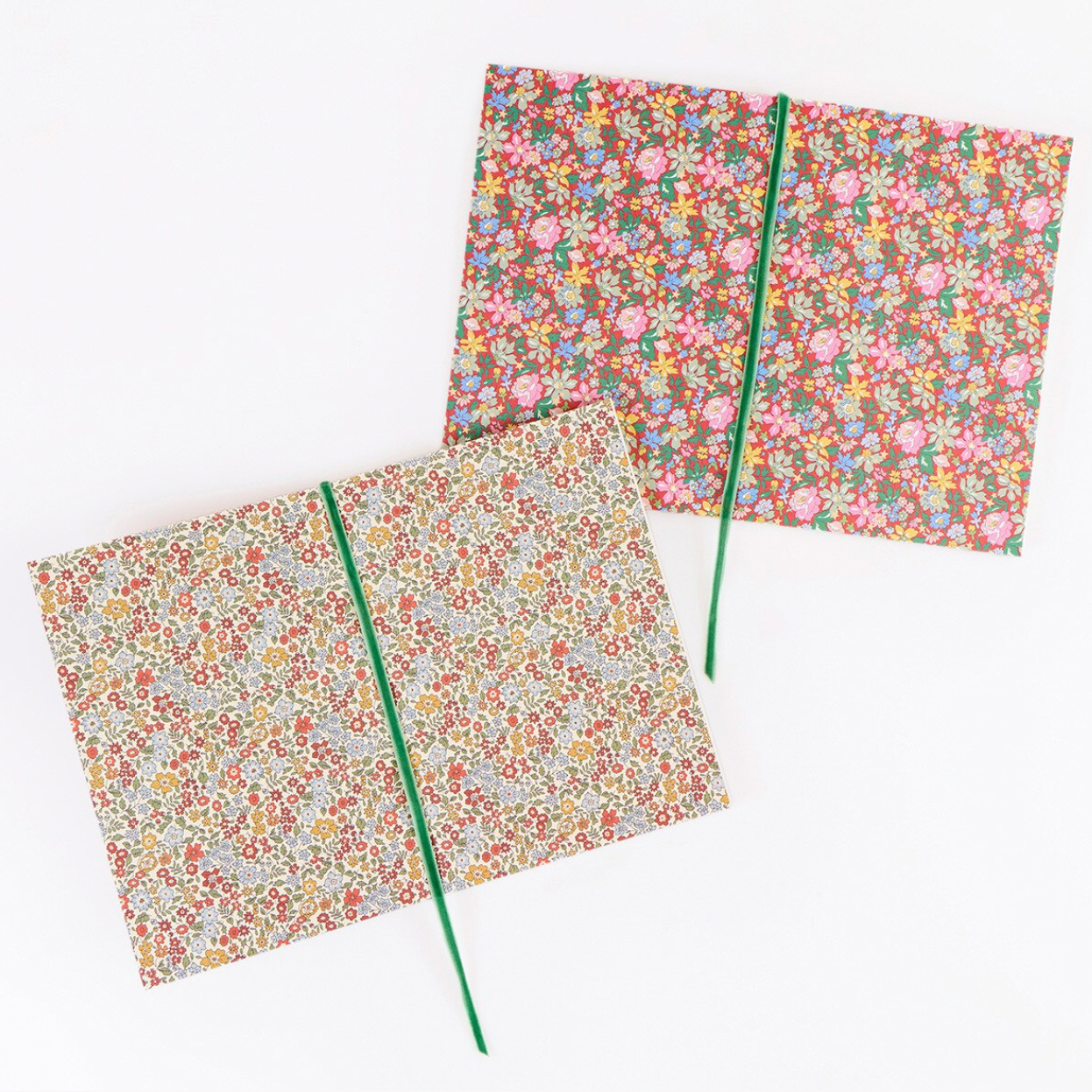 Two floral-patterned softcover notebooks with green elastic closure bands, displayed on a clean white background.