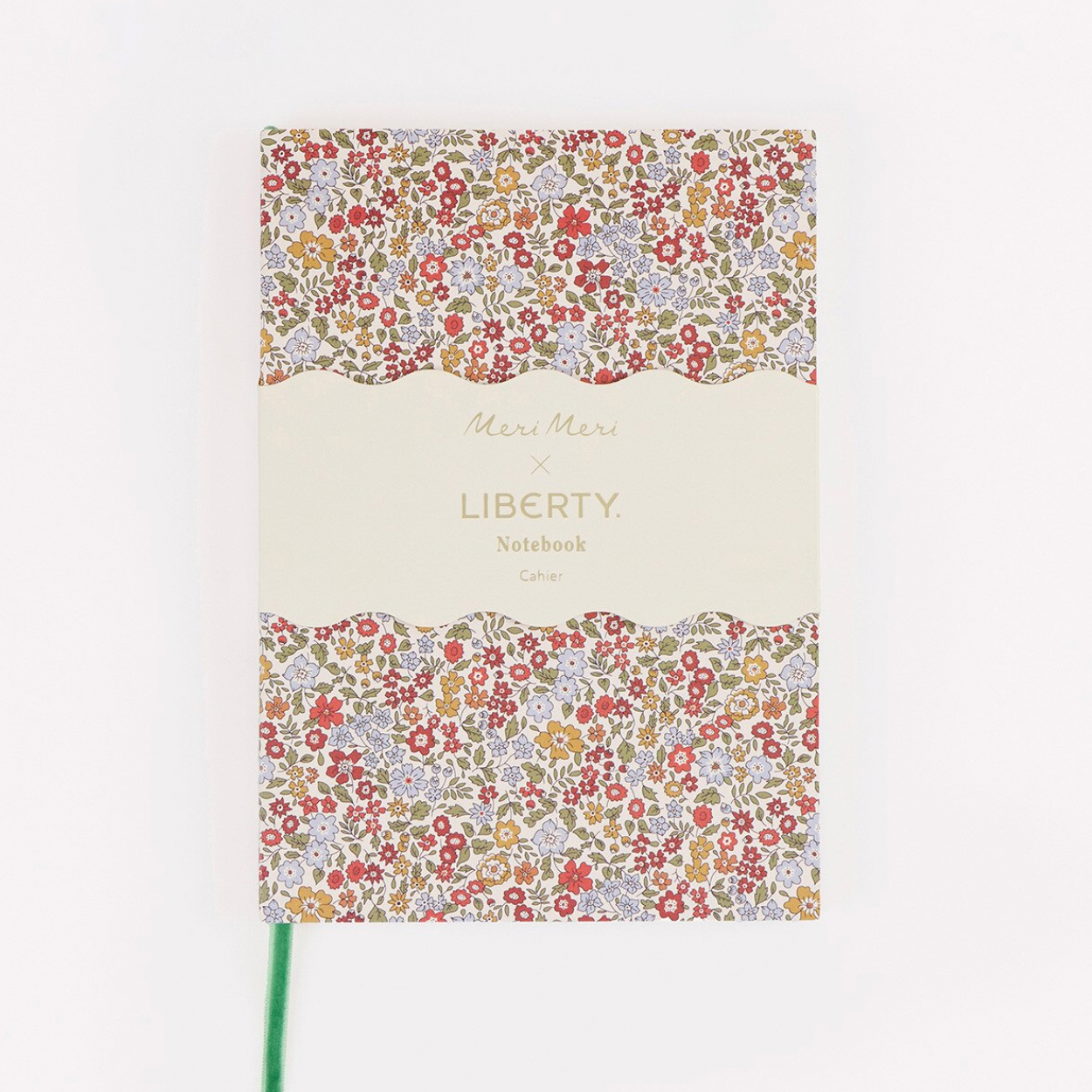 A notebook with a cream-colored center label and a busy floral pattern border in red, blue, yellow, and green, featuring the text 'Merry Merrily x LIBERTY Notebook' on the cover.