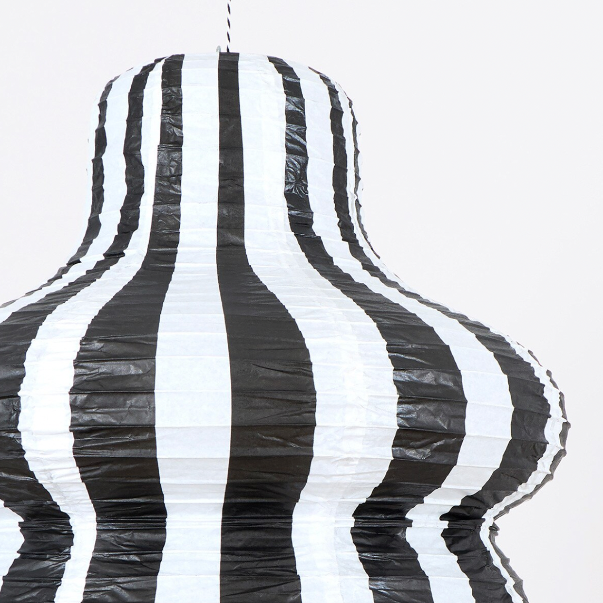 A black and white vertically striped paper lantern or hanging decoration shown against a plain light background.