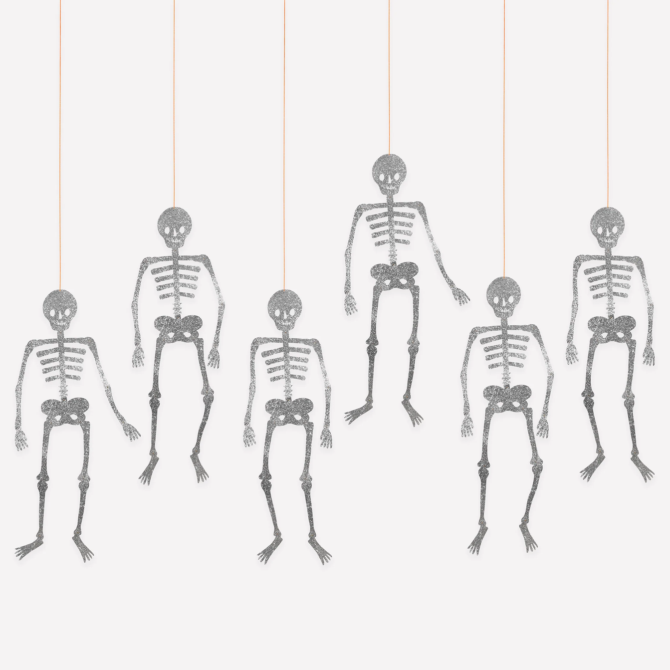 Five gray hanging skeleton decorations suspended by thin strings against a plain light background.