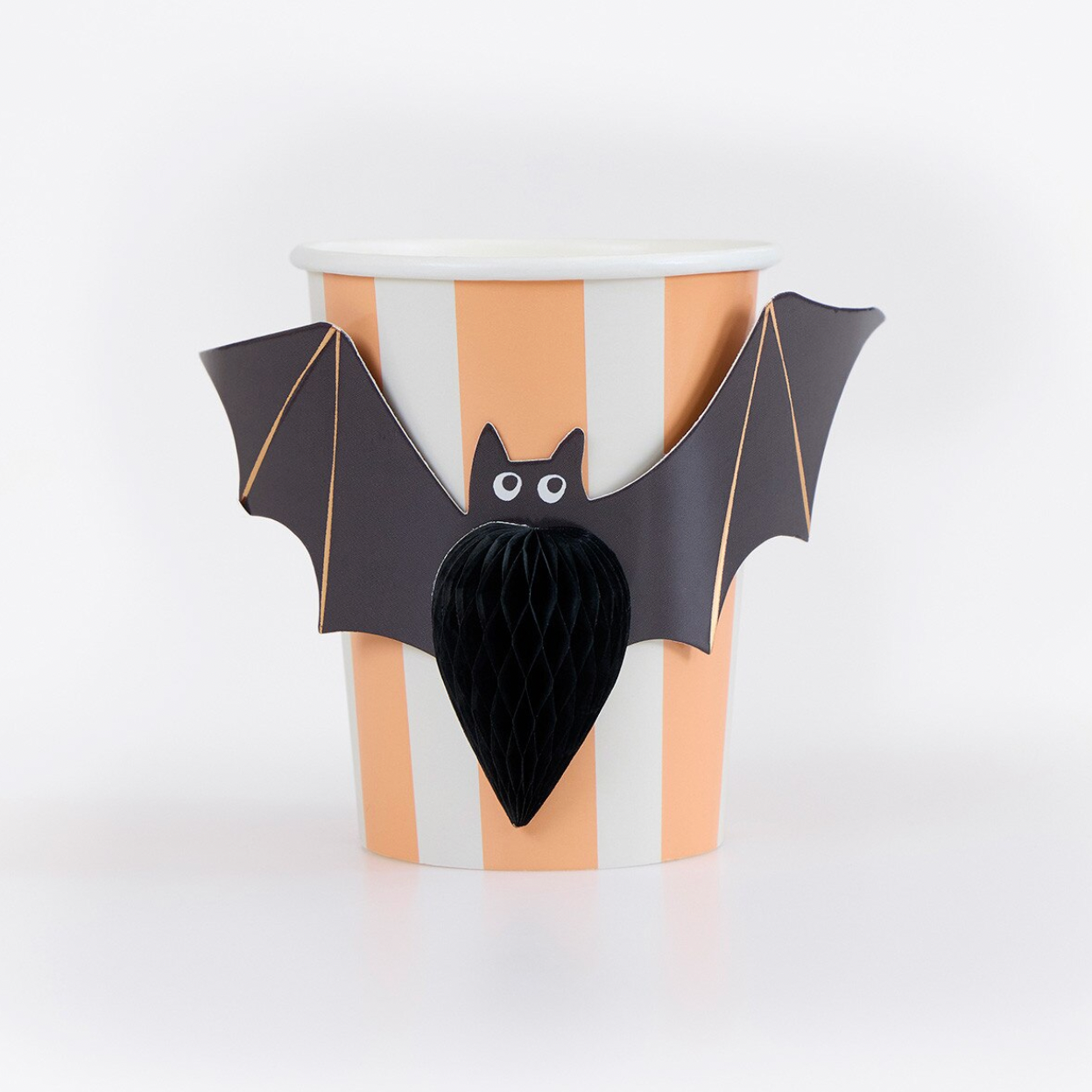 A Halloween-themed paper cup with vertical peach and white stripes, decorated with a black bat figure that has spread wings and a honeycomb-style black tail, set against a plain white studio background.