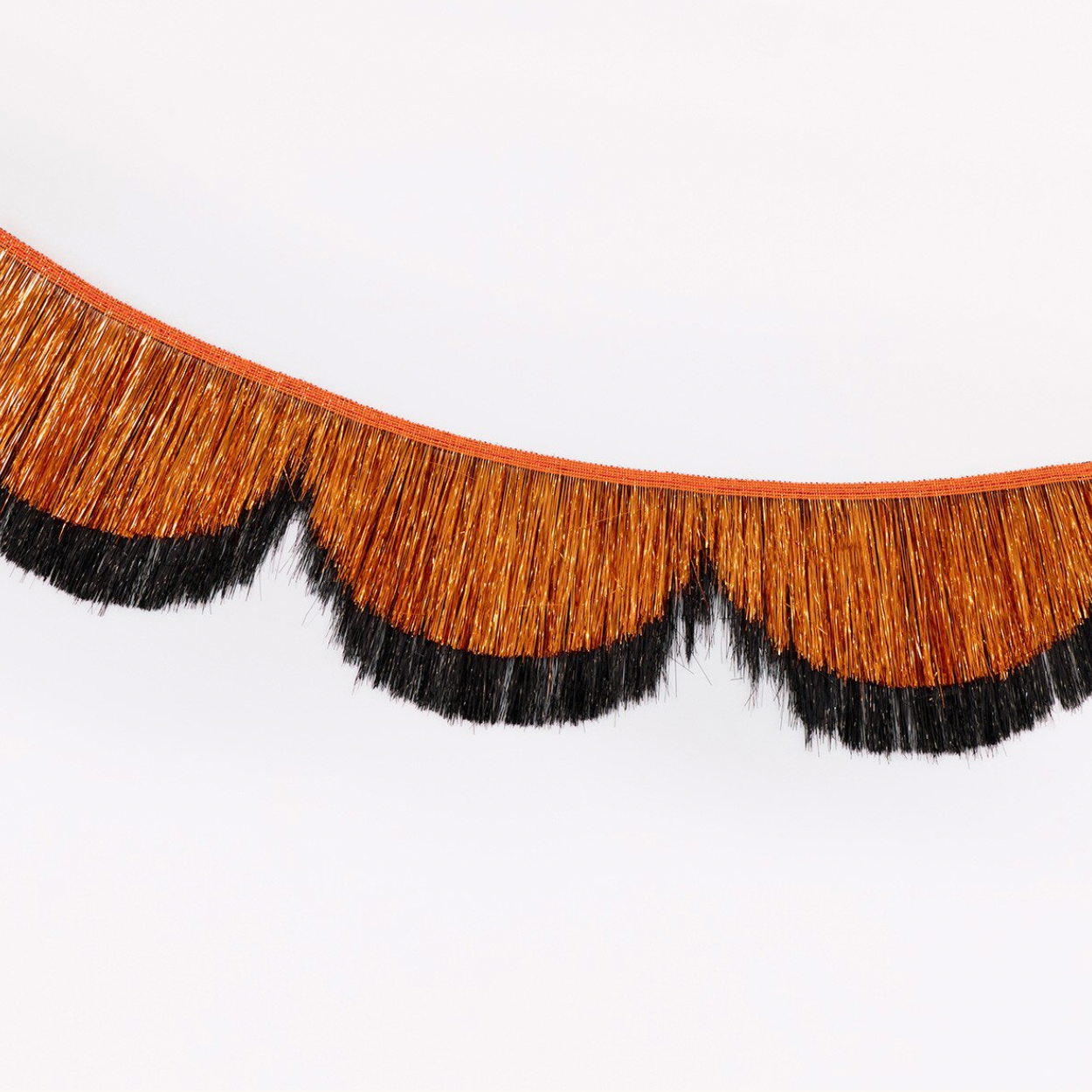 A decorative fringe trim with a warm brown center and black scalloped fringe along the bottom edge, shown against a plain white background.