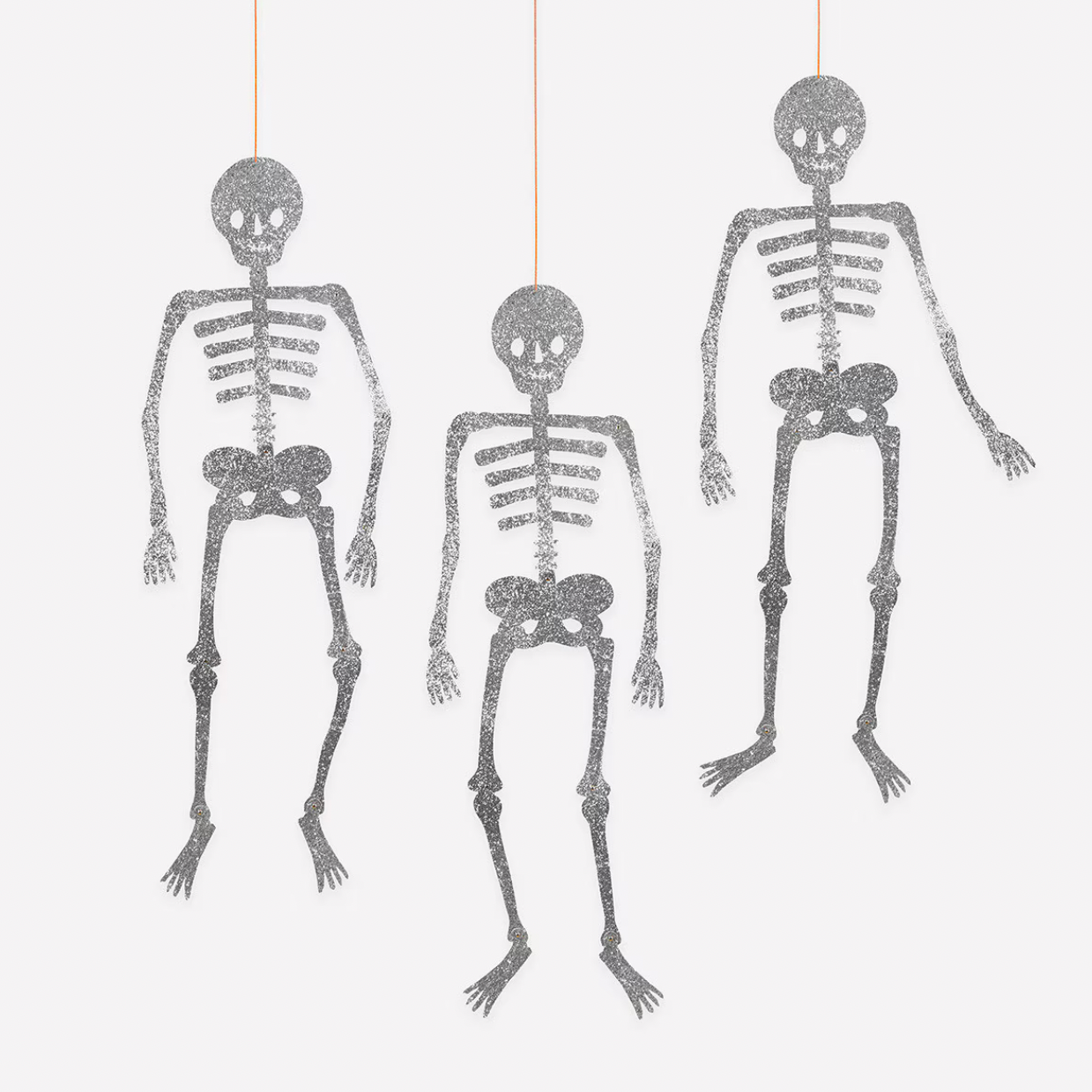 Three hanging skeleton decorations in different sizes on a plain white background.