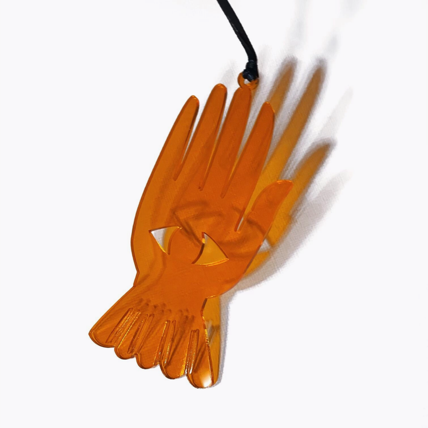 An orange translucent acrylic pendant shaped like a stylized hand with a bird motif, hanging from a black cord against a white background.