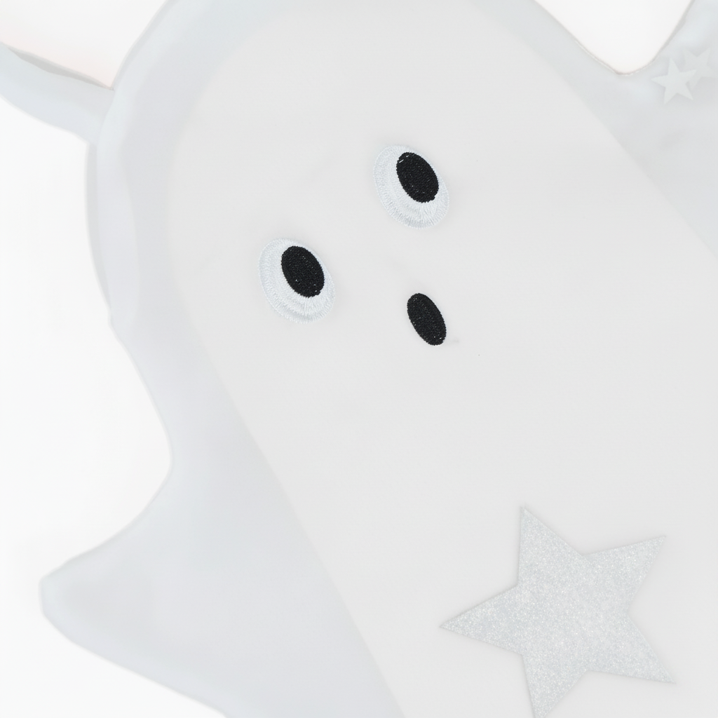 A close-up of a white ghost-shaped plush toy or pillow with embroidered black eyes and mouth, plus a glittery silver star detail, shown on a white background.