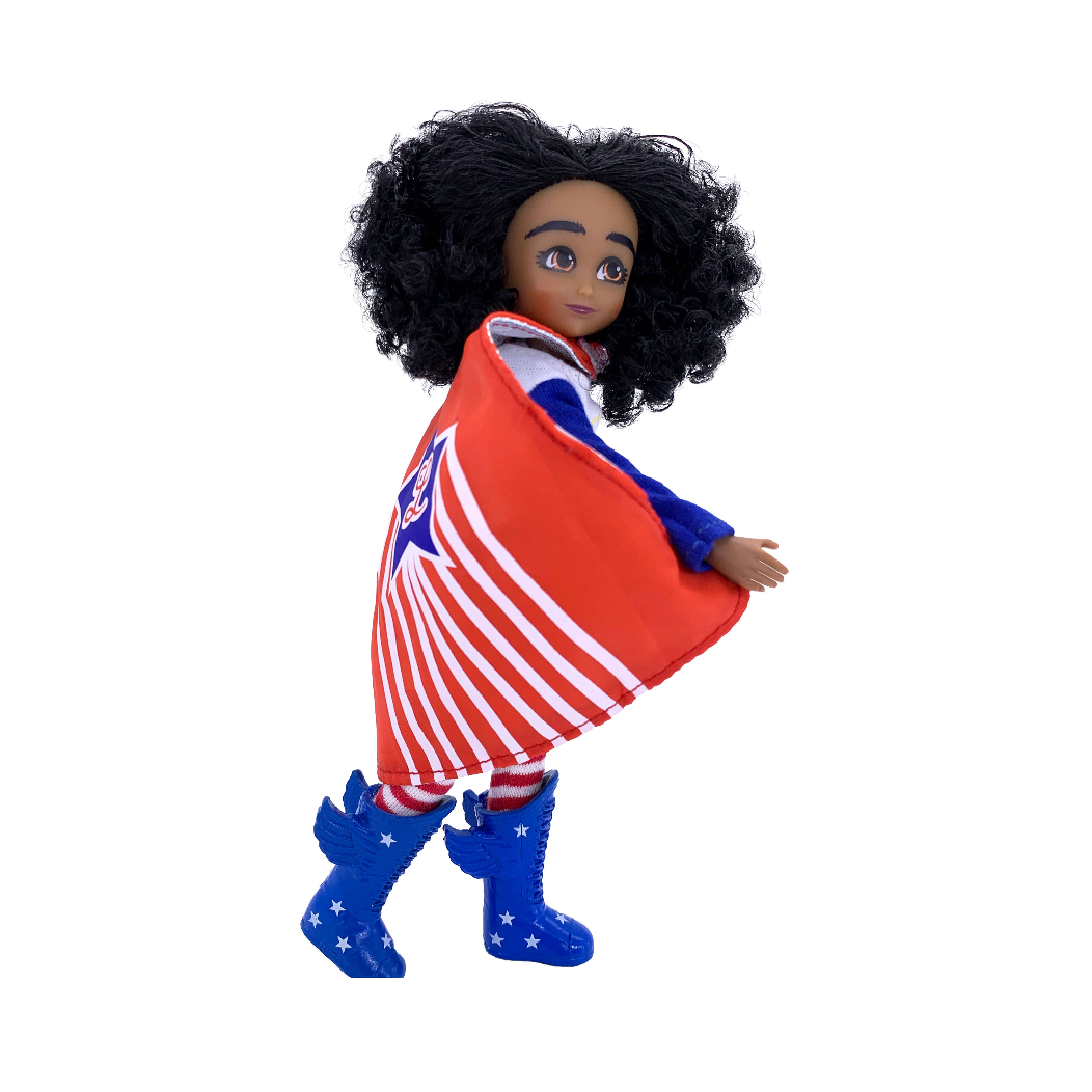 A doll or toy figure with dark curly hair, wearing a red, white, and blue patriotic cape and blue boots, shown against a plain white background.
