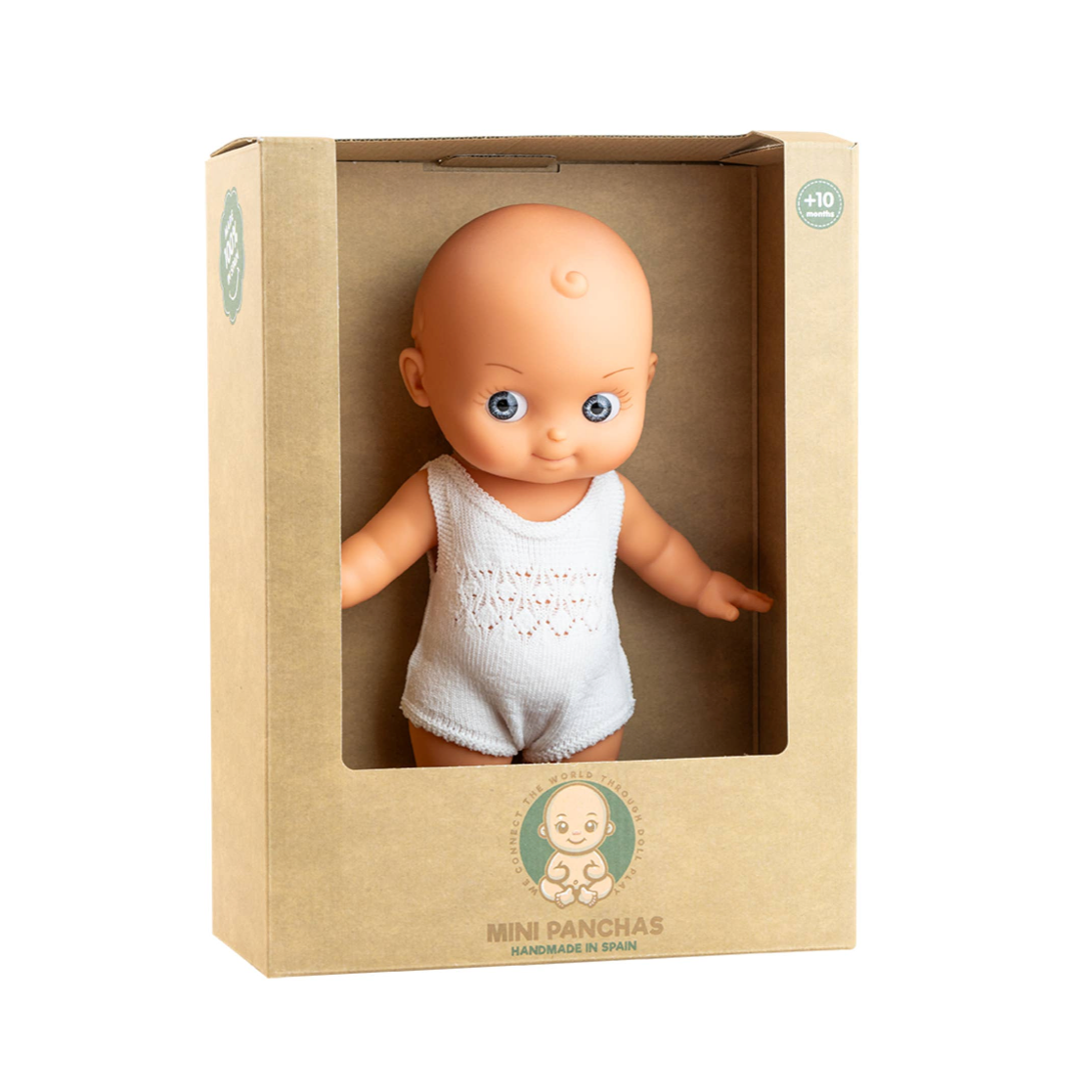 A baby doll with blue eyes and a bald head, wearing a white tank top, displayed inside a beige cardboard window box. The box has a circular green logo near the bottom.